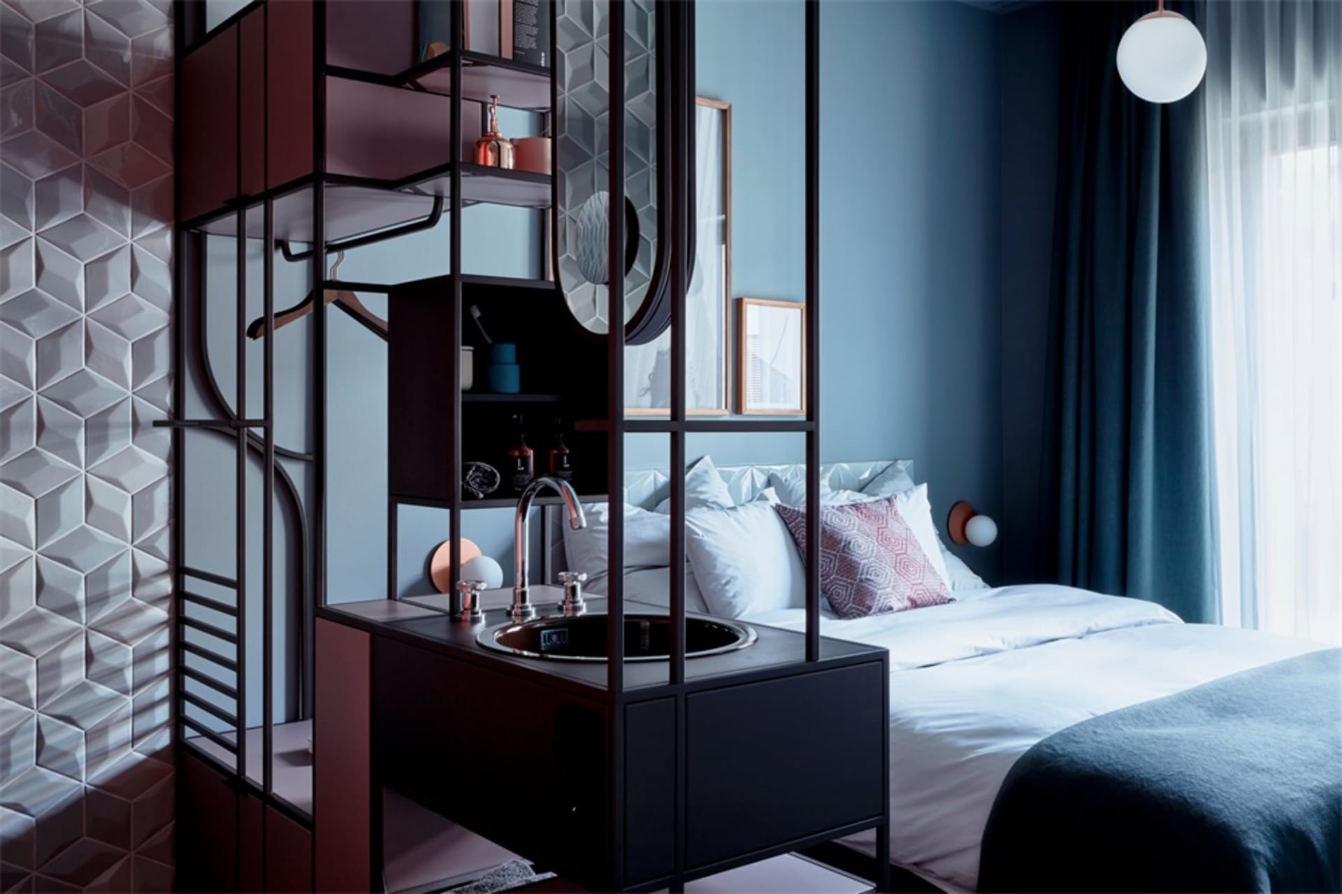 A modern bedroom features a metal and glass vanity unit with a sink and mirror, complemented by a comfortable bed with white