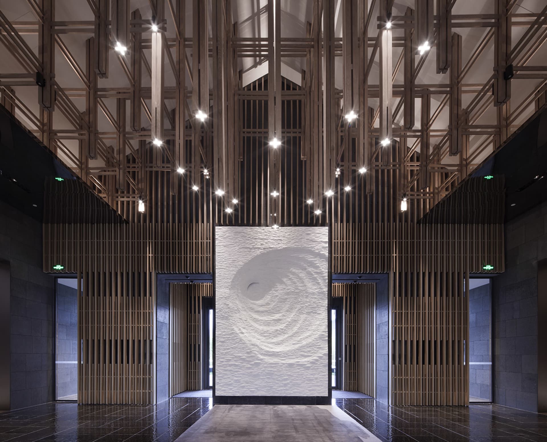 A modern lobby with wooden walls and a central spiral pattern on a white wall.