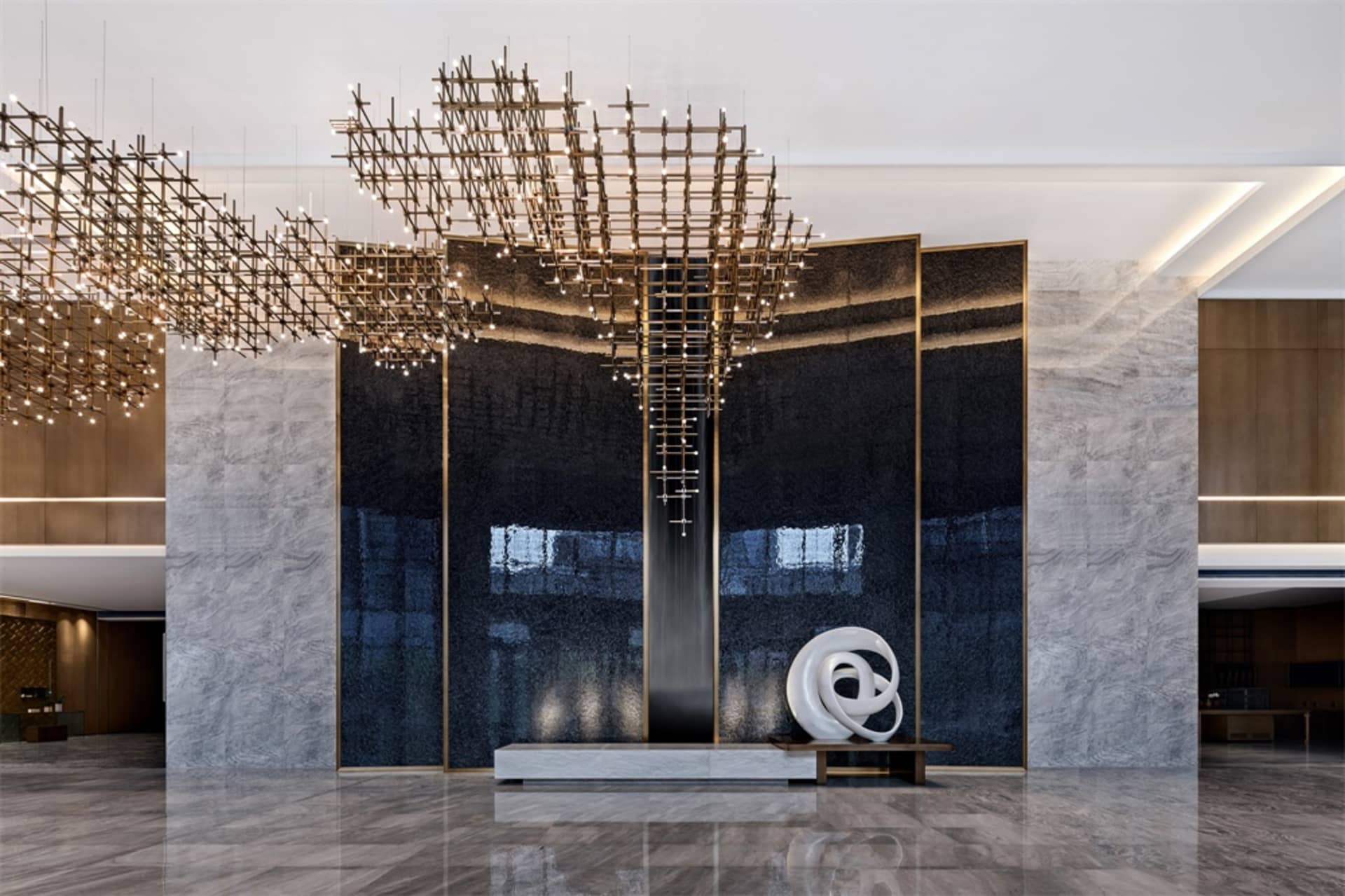 A modern lobby with a contemporary metal chandelier and black glass wall.