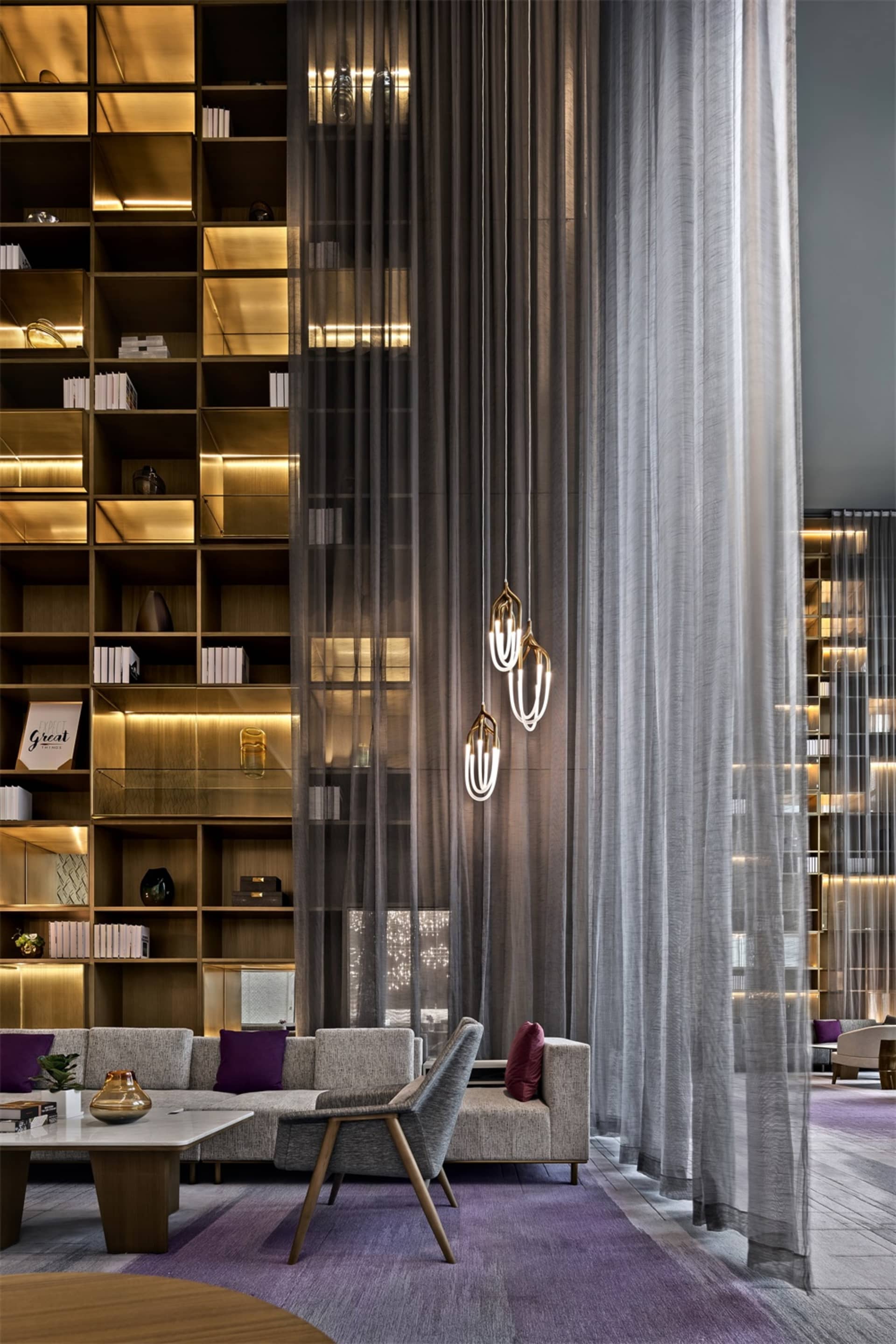 Interior view of a modern lobby featuring wooden furniture, glass walls, and fabric curtains.
