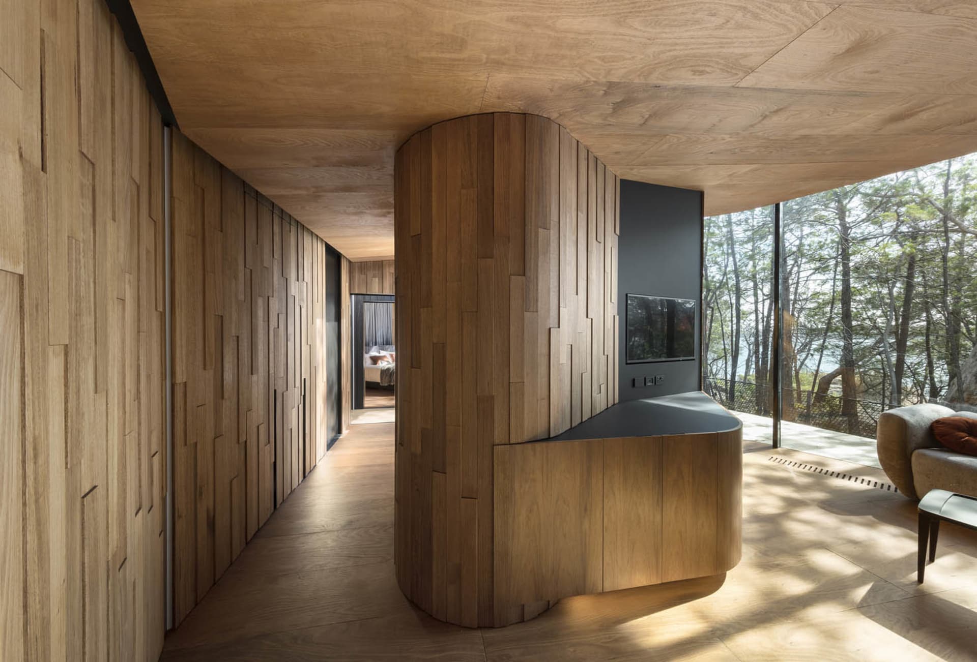 A modern interior space featuring wooden walls and flooring with a central wooden pillar.