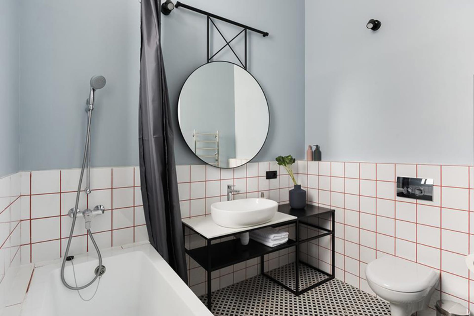 Modern minimalist bathroom featuring white and black tiled floor, white bathtub, and white sink with black faucet.