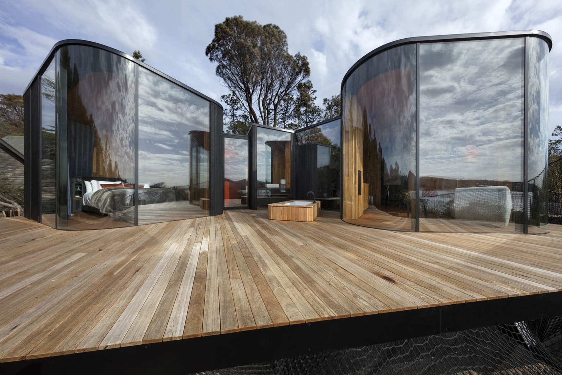 A modern residential structure featuring large glass windows and wooden flooring.