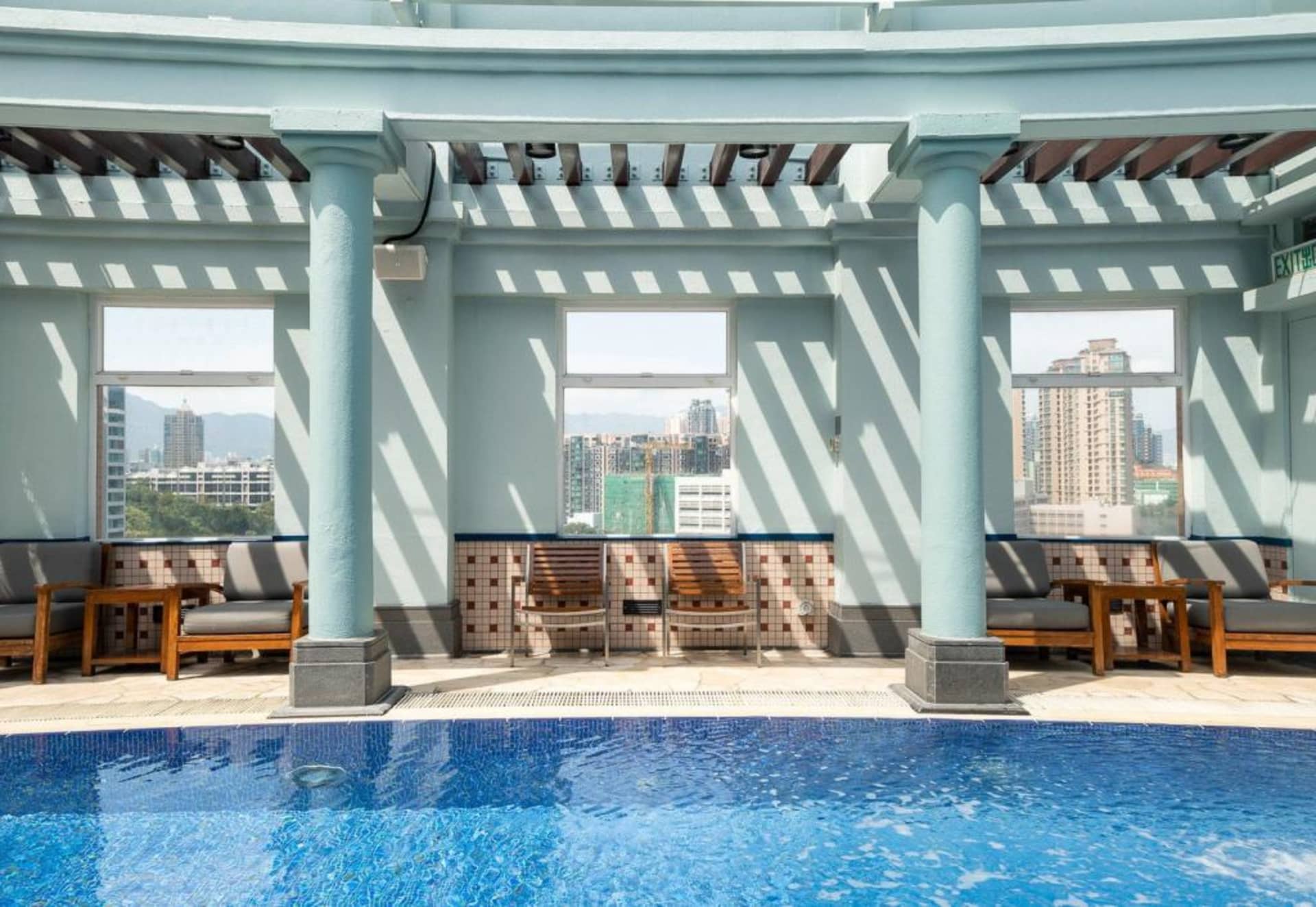 Roof top pool area featuring concrete pillars, tiled walls, and glass windows