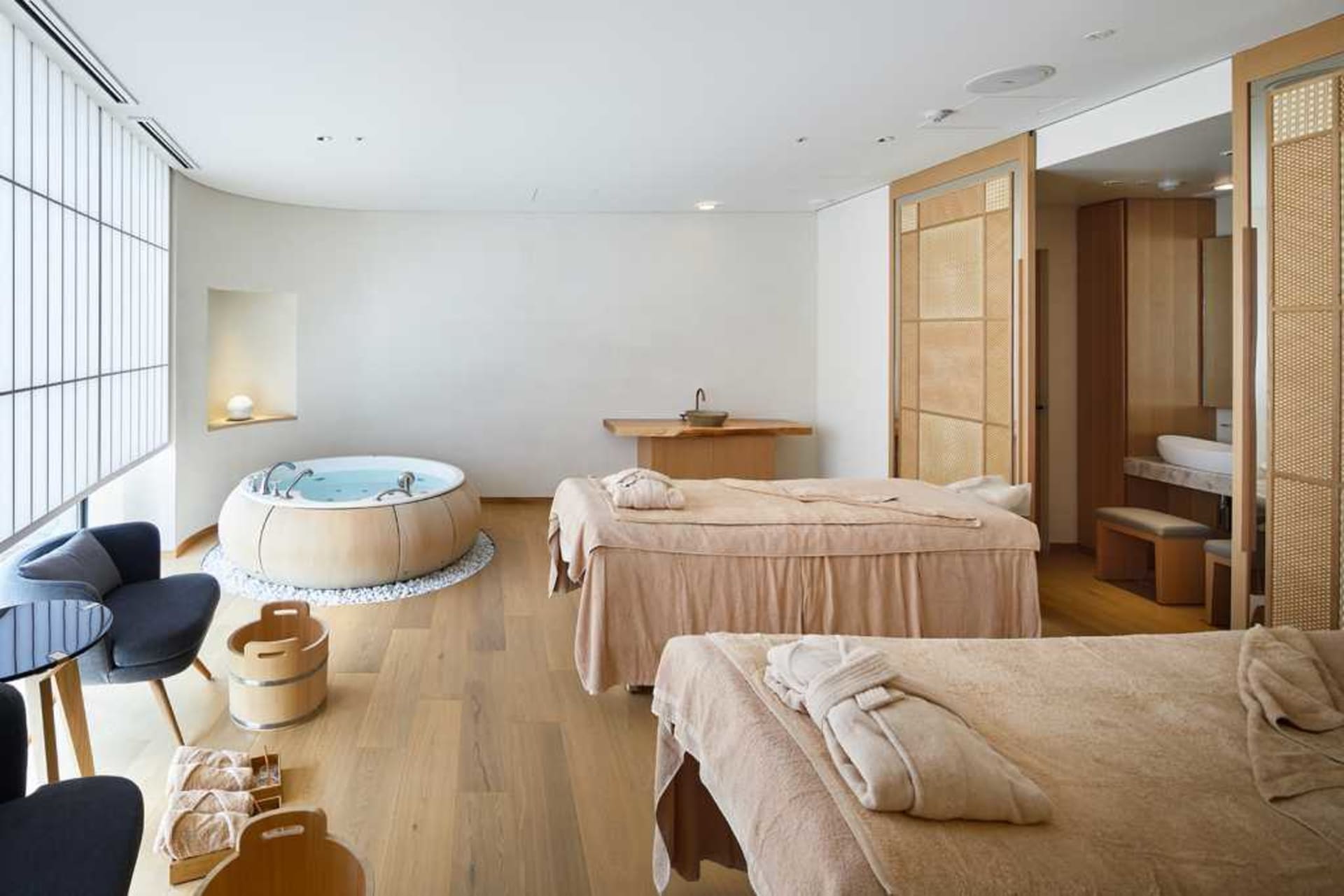 A serene spa interior featuring a massage room with wooden furniture and a round bathtub.
