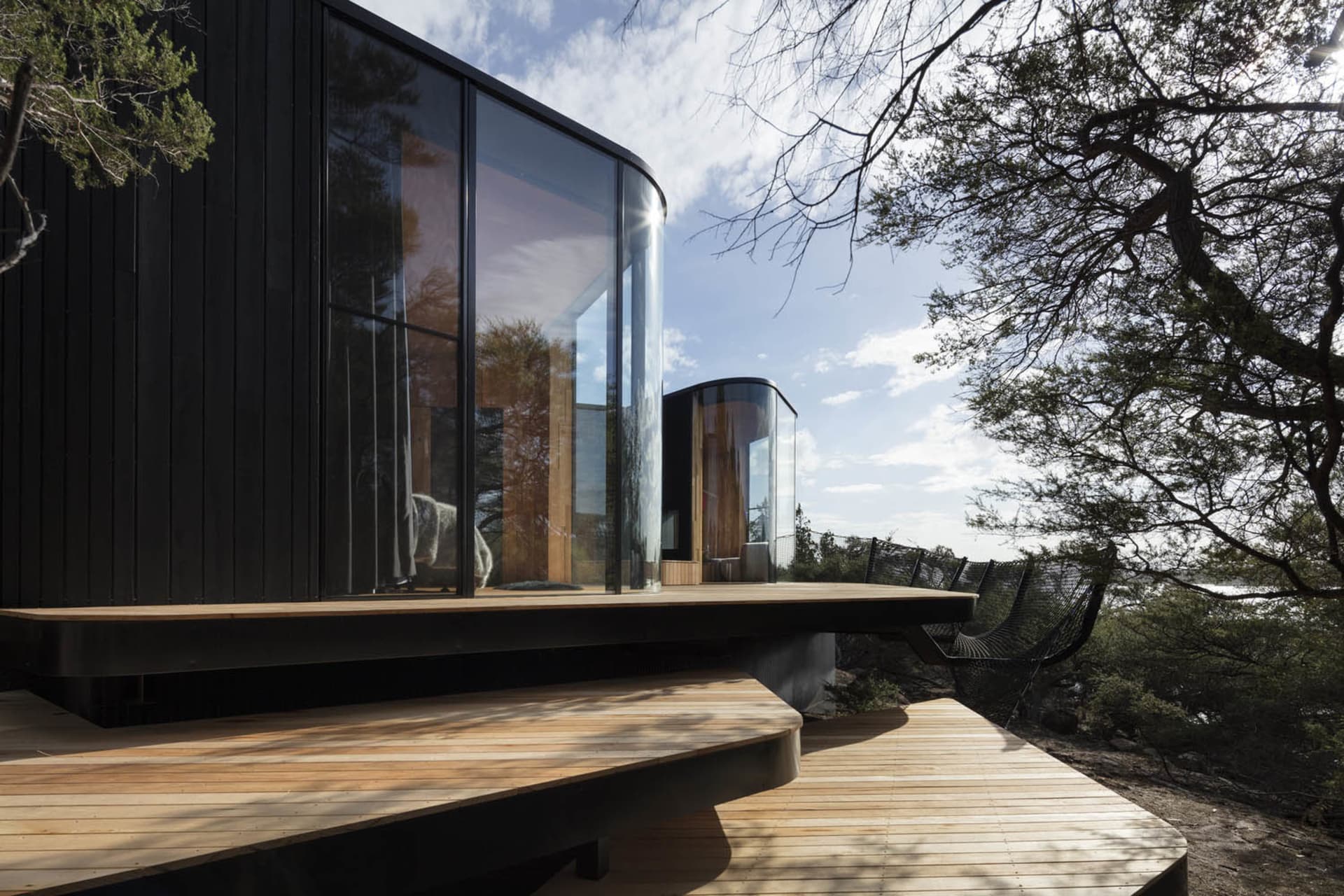Modern house exterior with black wood paneling and a wooden terrace.