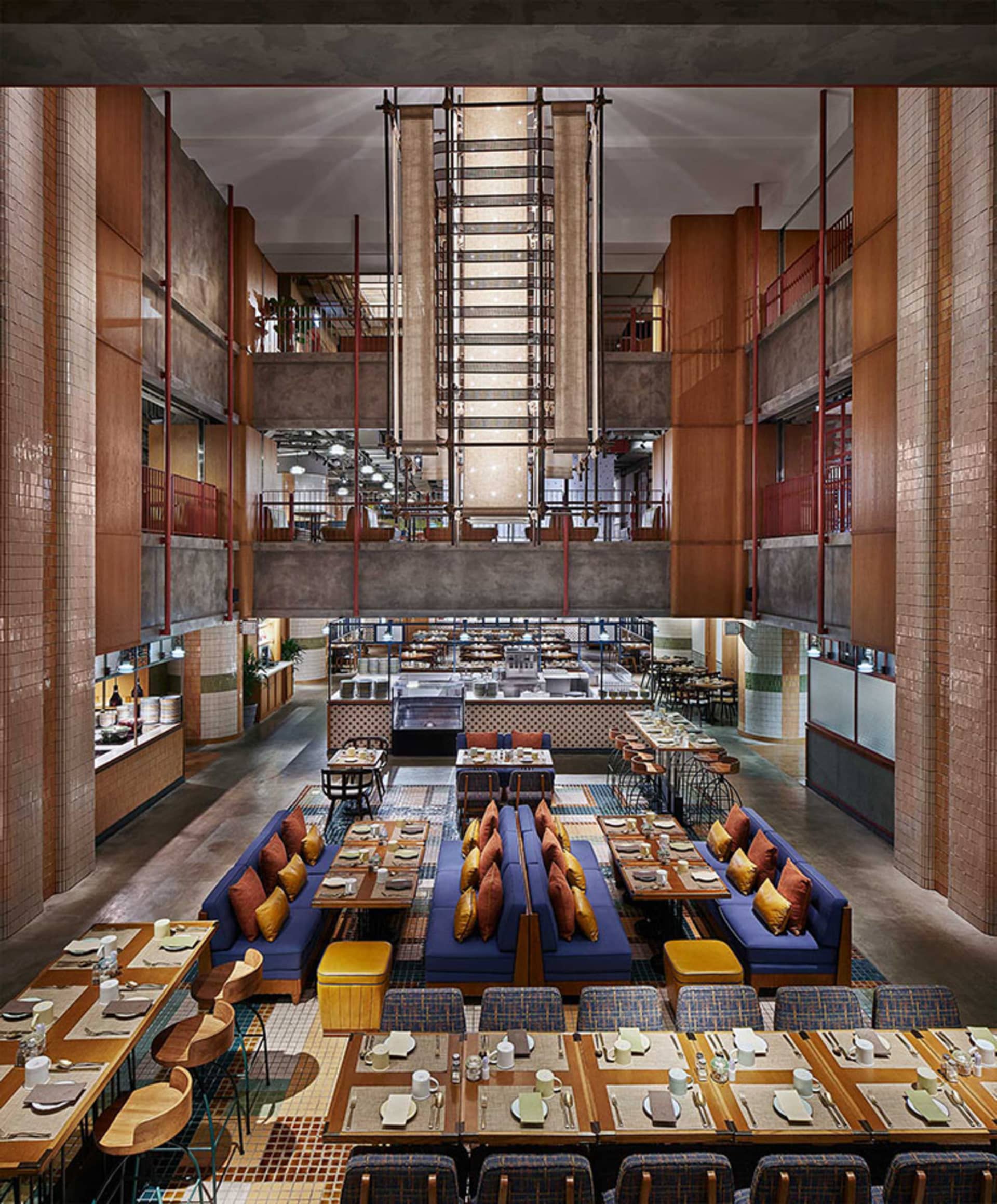 Modern restaurant with industrial design elements, featuring wooden tables, metal chairs, and concrete flooring.