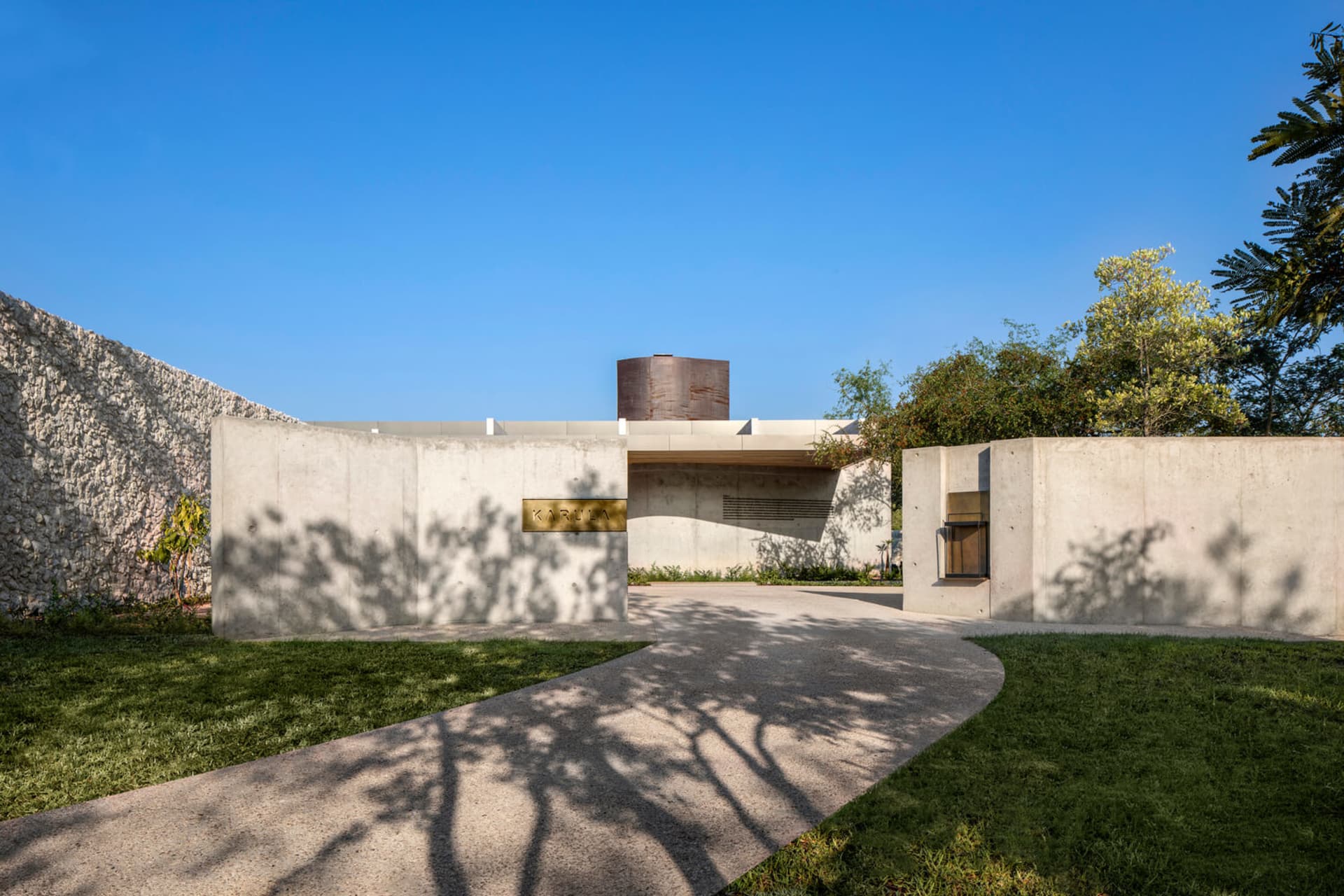 Concrete entrance with stone accent wall, trees, and grass
