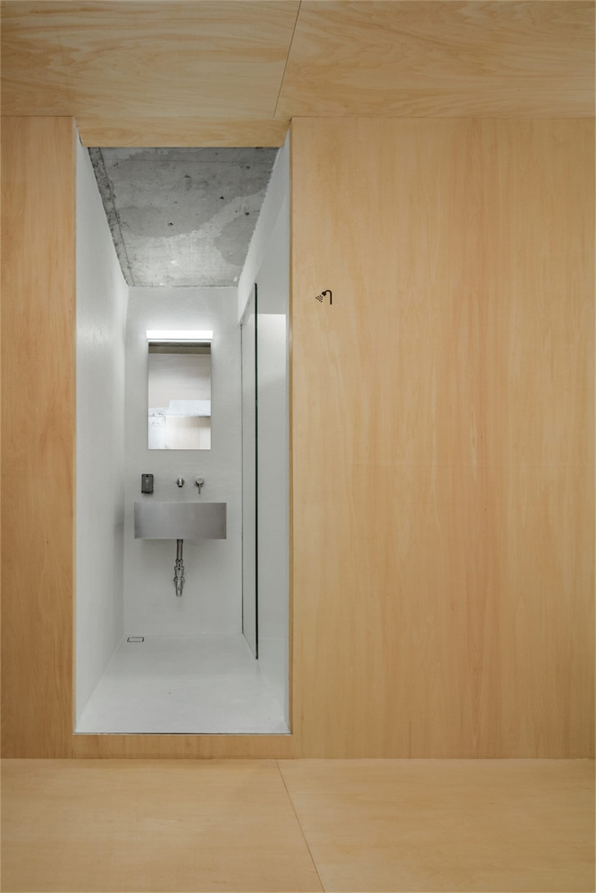 Modern minimalist bathroom with white walls, wooden walls and floor, and a concrete ceiling.