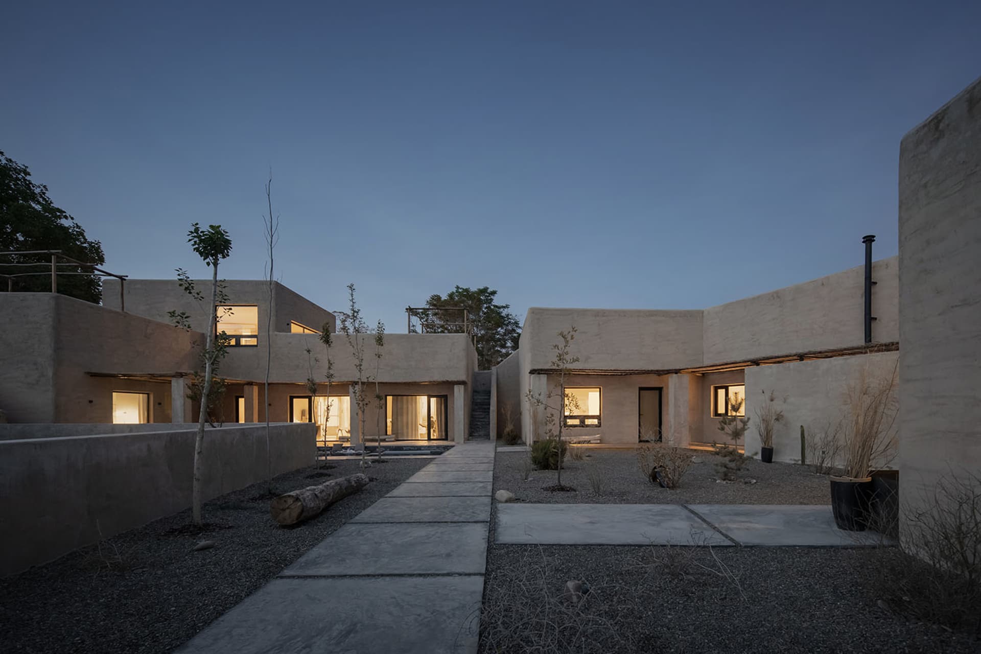 A modern residential house with concrete walls and a courtyard at dusk.