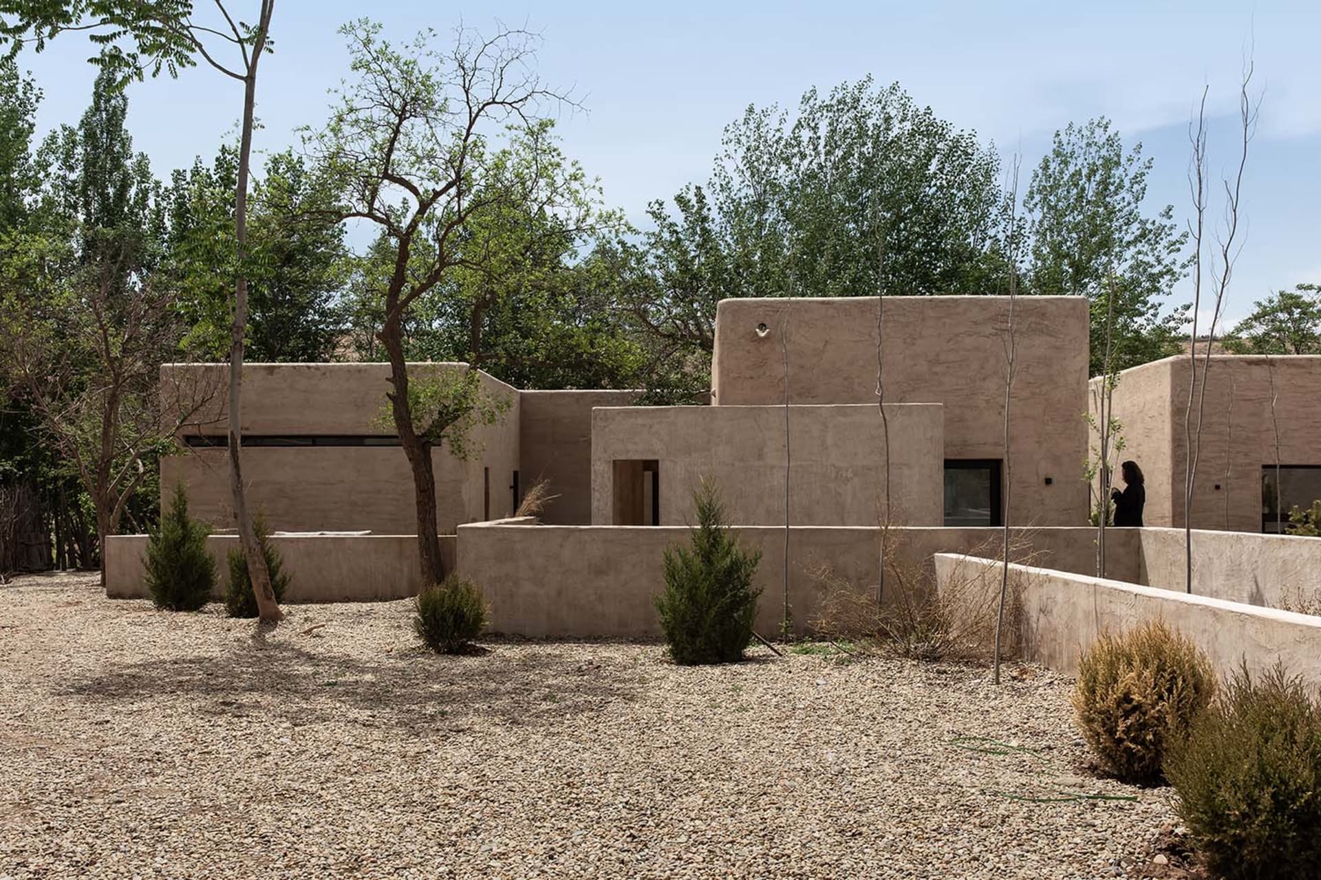 A modern house with stucco exterior and surrounding greenery.