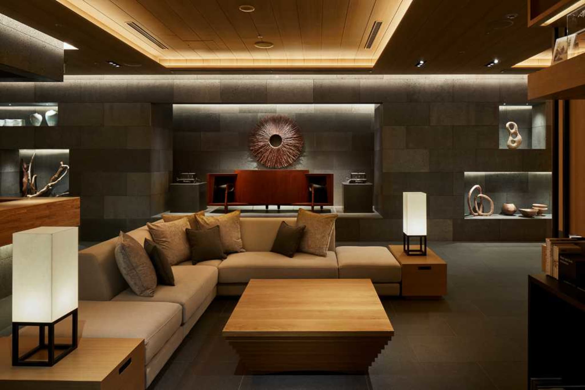 Contemporary living room with minimalist design, featuring wooden furniture, concrete walls, and metal accents.