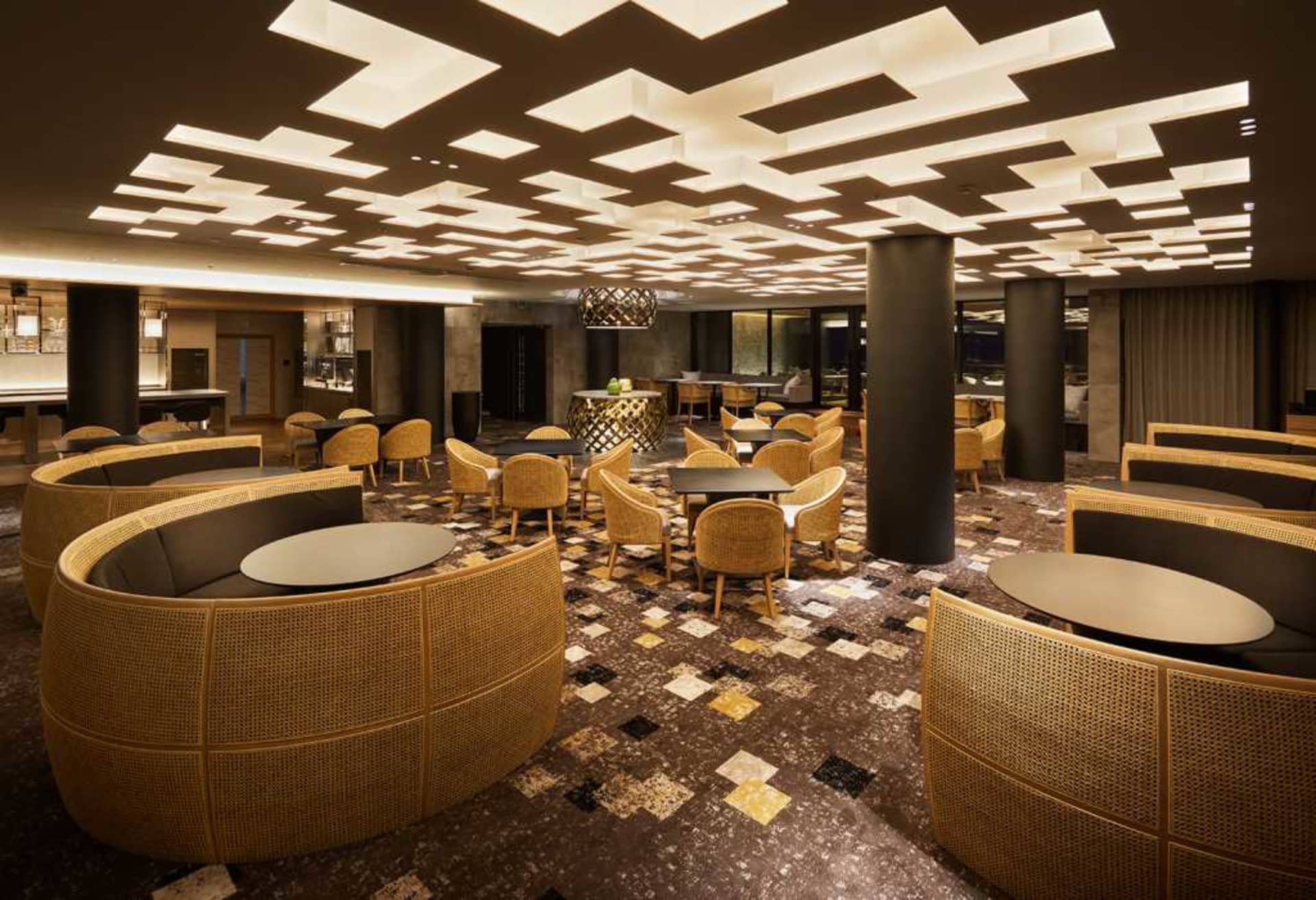 Interior design of a modern cafe bar with wicker furniture and geometric ceiling lights.