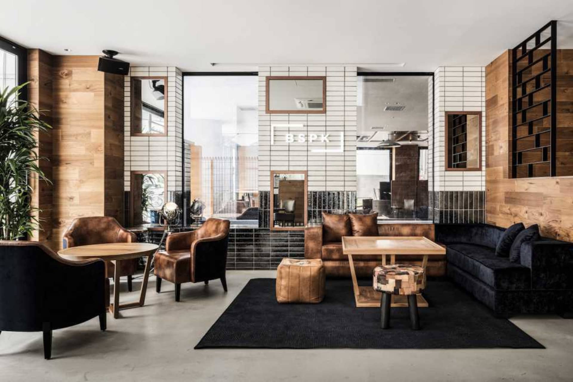 An industrial-style lobby with wood, leather furniture, and concrete flooring.