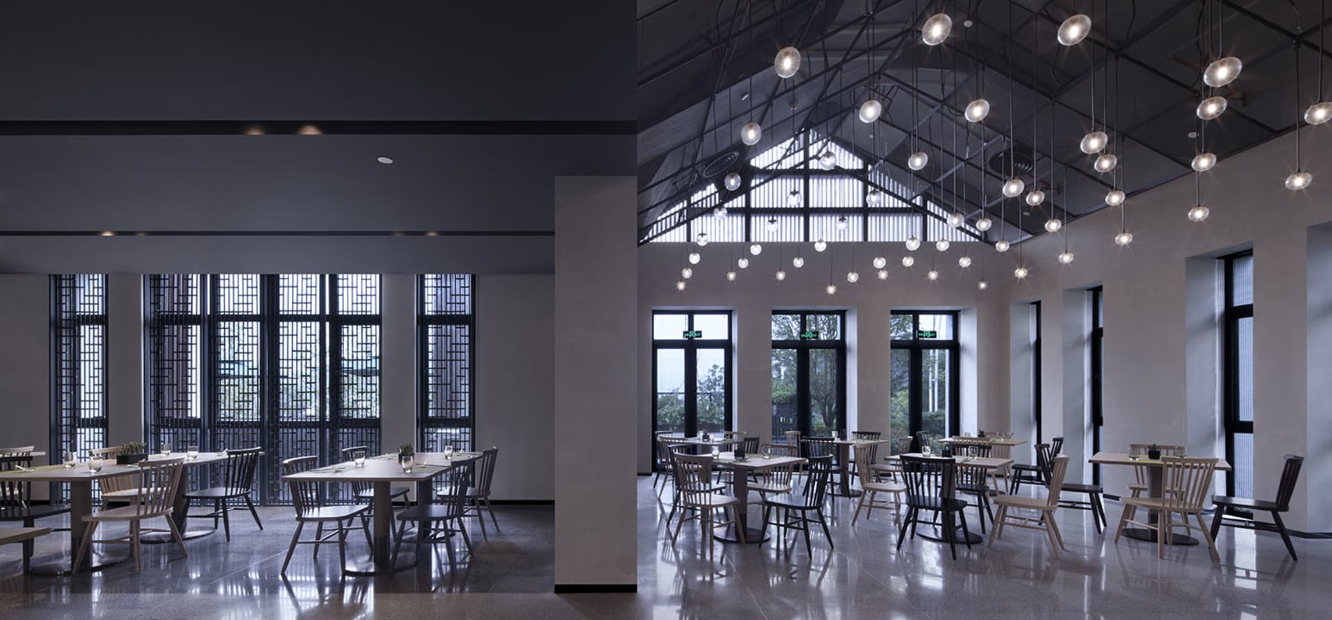 Modern industrial restaurant interior featuring metallic finishes, glass elements, and concrete surfaces.