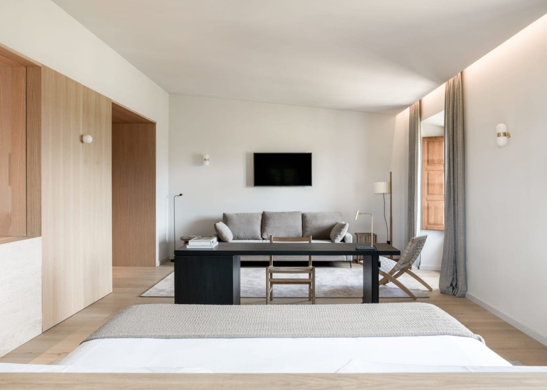 A minimalist living room featuring a wooden floor, light-colored walls, a brown leather sofa, and a wooden coffee table.