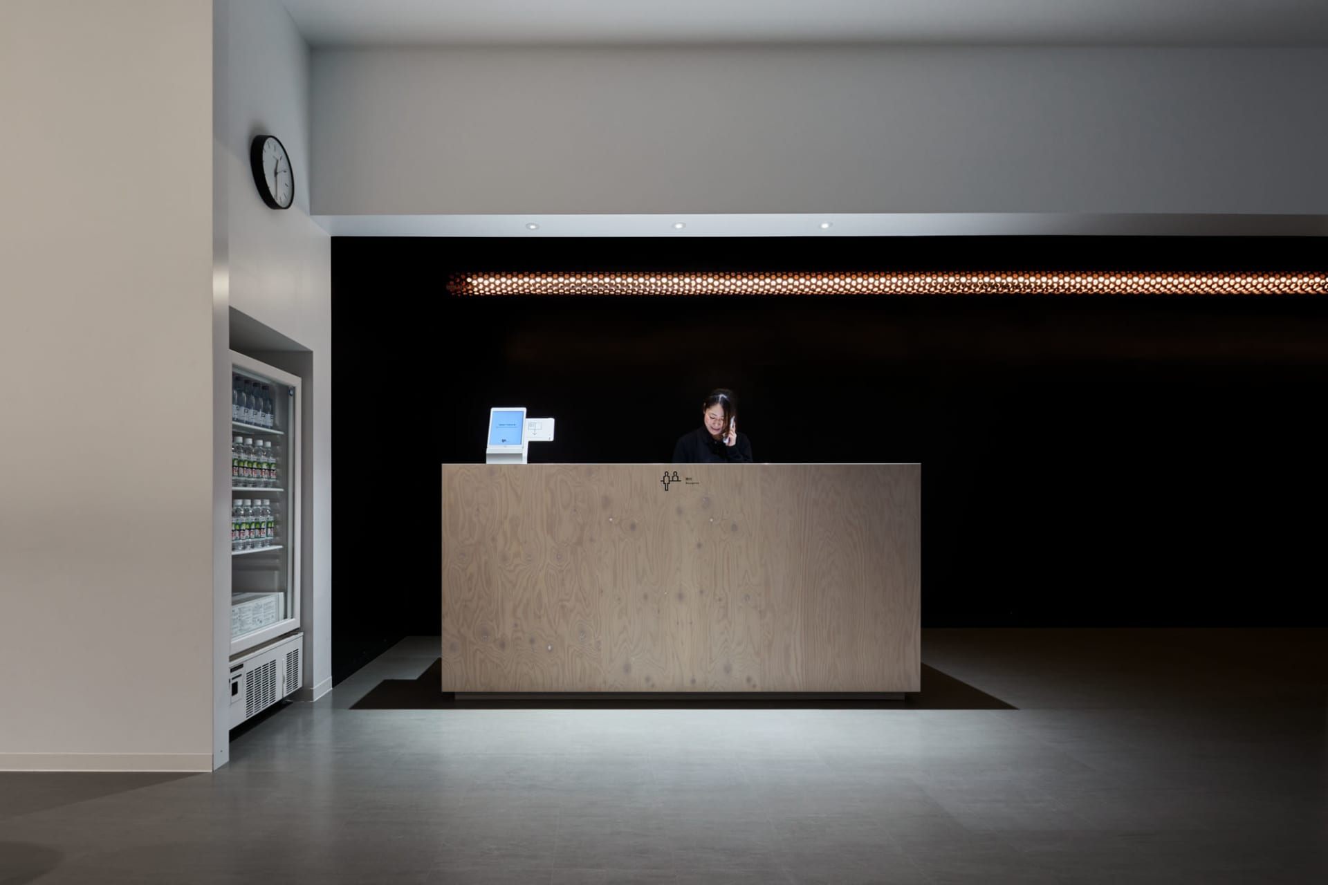 A minimalist reception desk with a wood finish located in a modern lobby setting.
