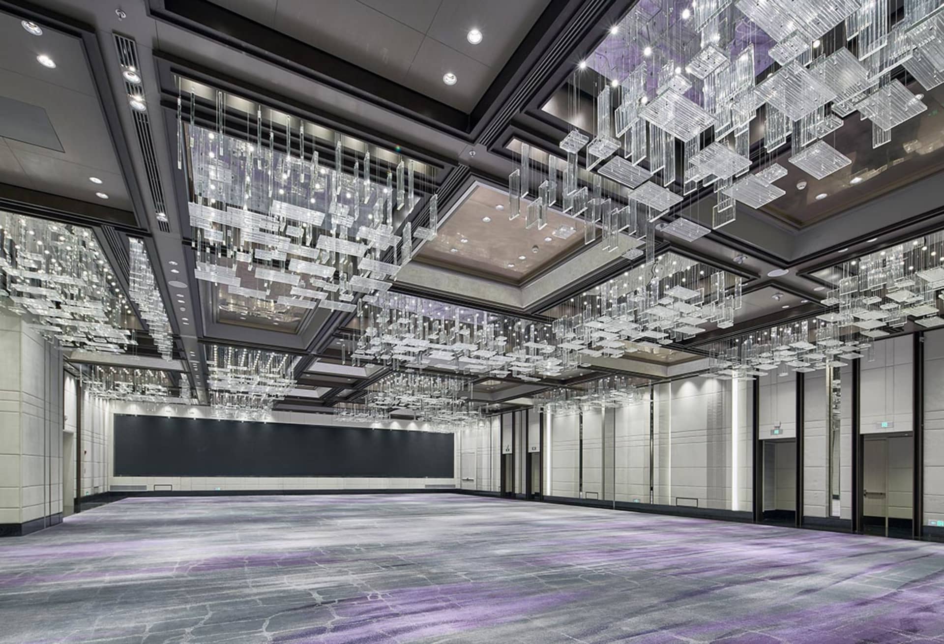 A spacious, industrial-style conference hall with metallic ceiling structures and a large, empty floor.