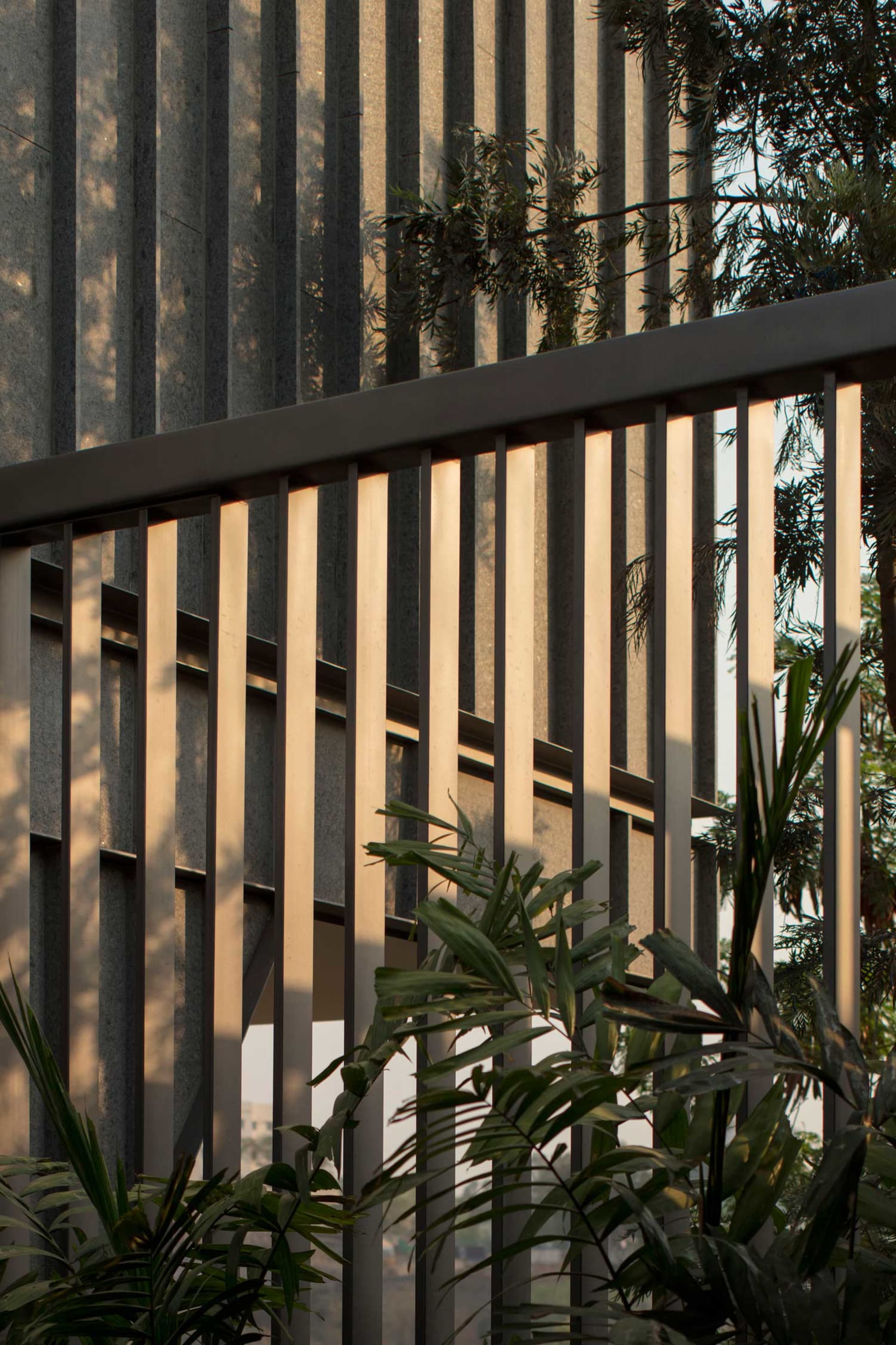 Detailed image of metallic striped architectural design element with lush greenery in the foreground.