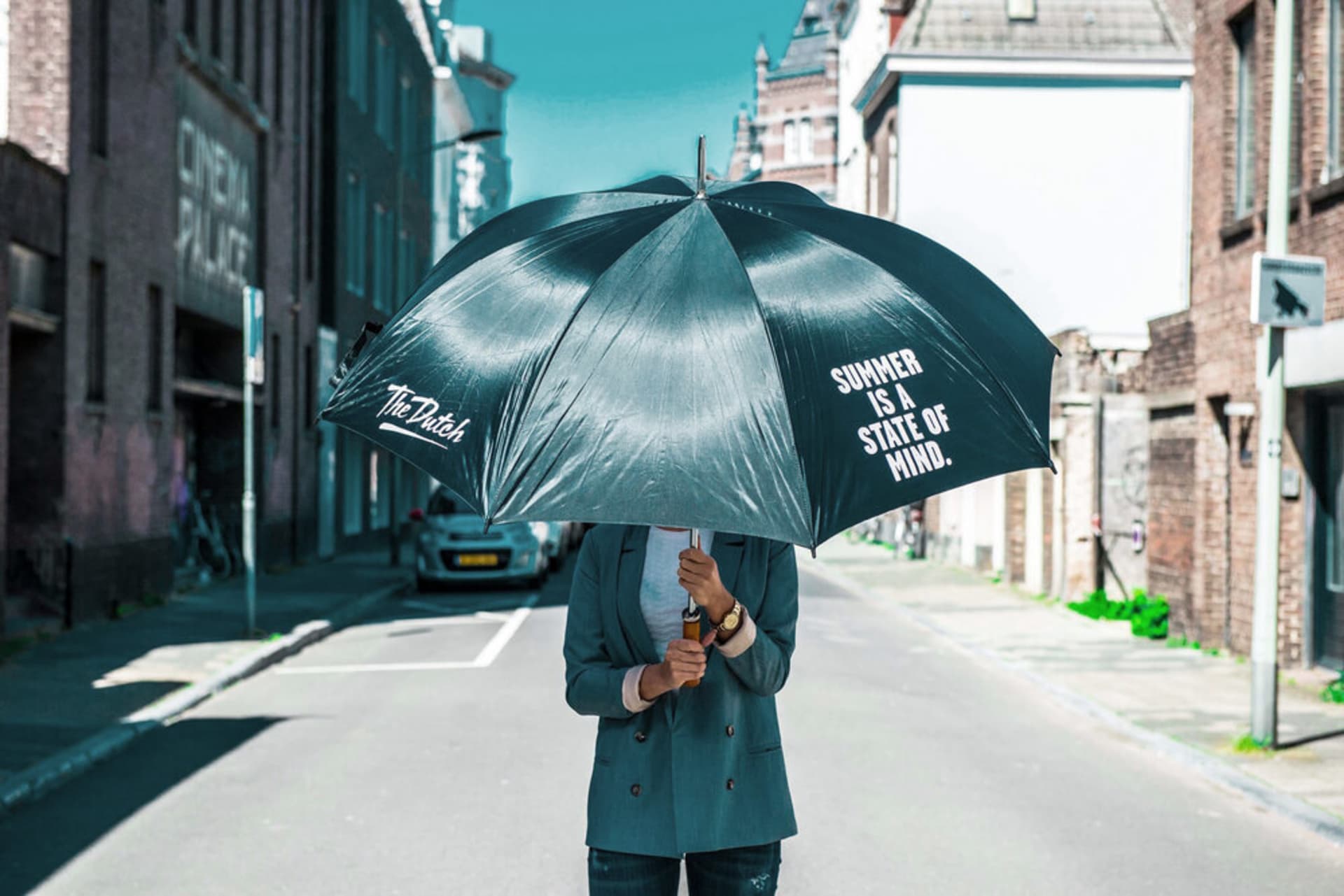 A person standing on a city street holding an umbrella with the text 'Summer is a State of Mind.'