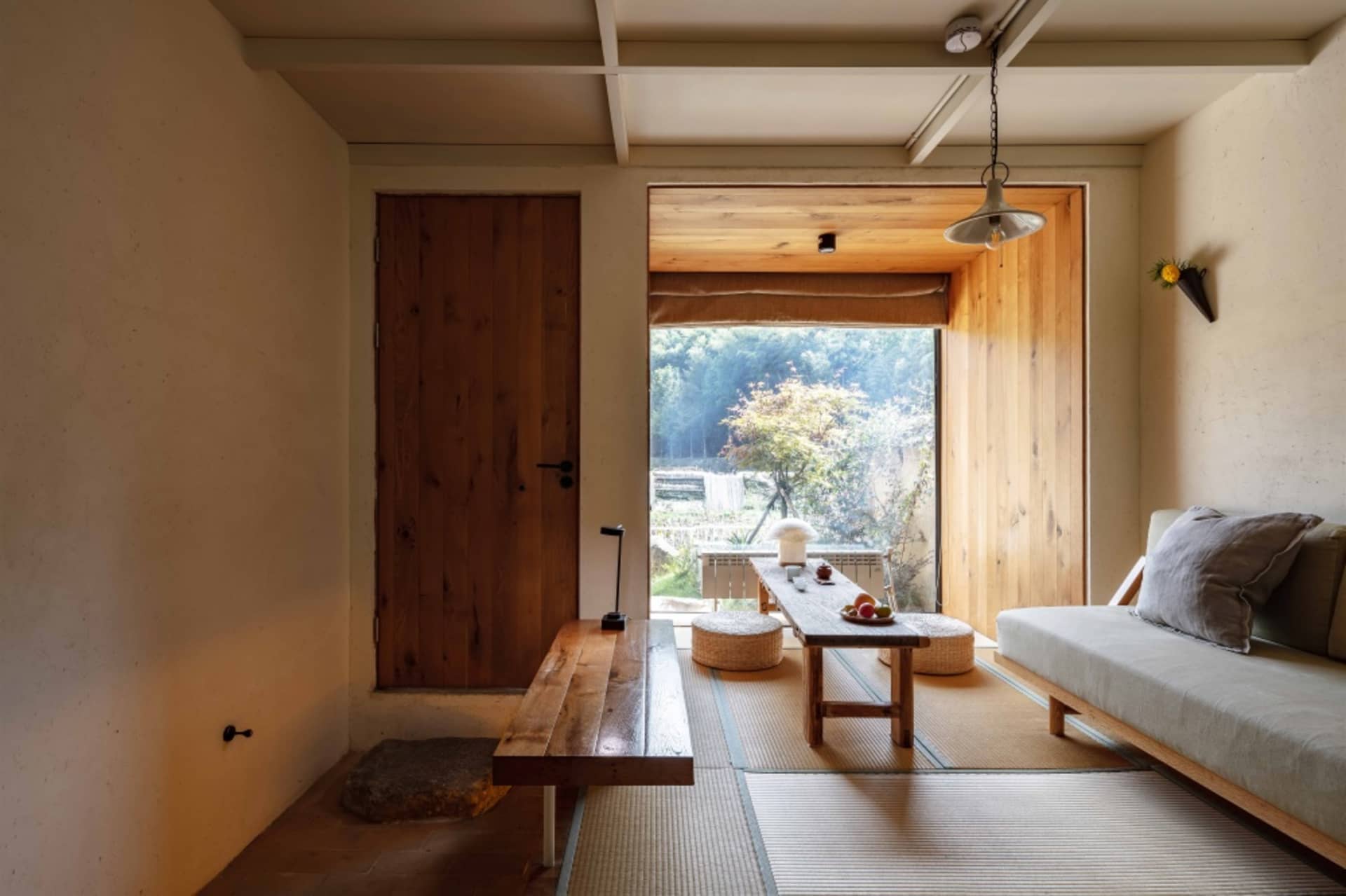 A minimalist living room with wooden furniture, bamboo accents, and concrete flooring.
