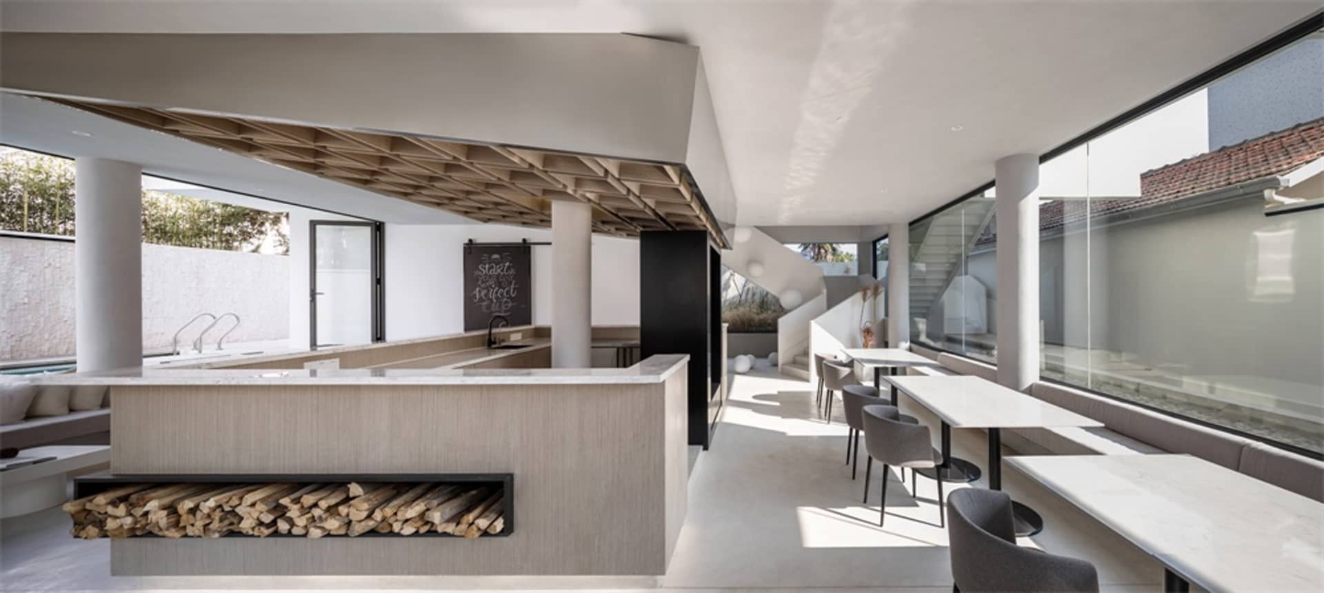 Modern espresso bar with concrete counter, glass shelves, and contemporary furniture.