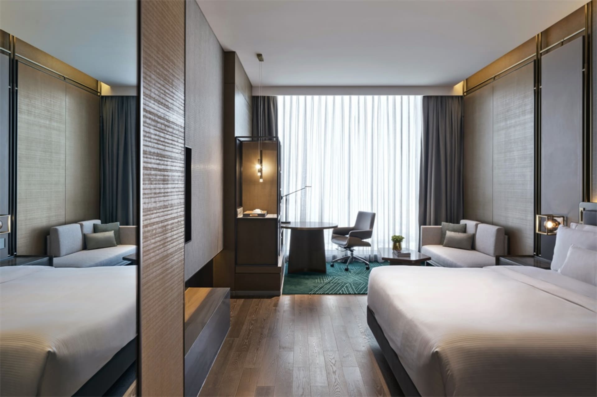 Modern hotel suite with a wooden floor, fabric furnishings, and glass windows.