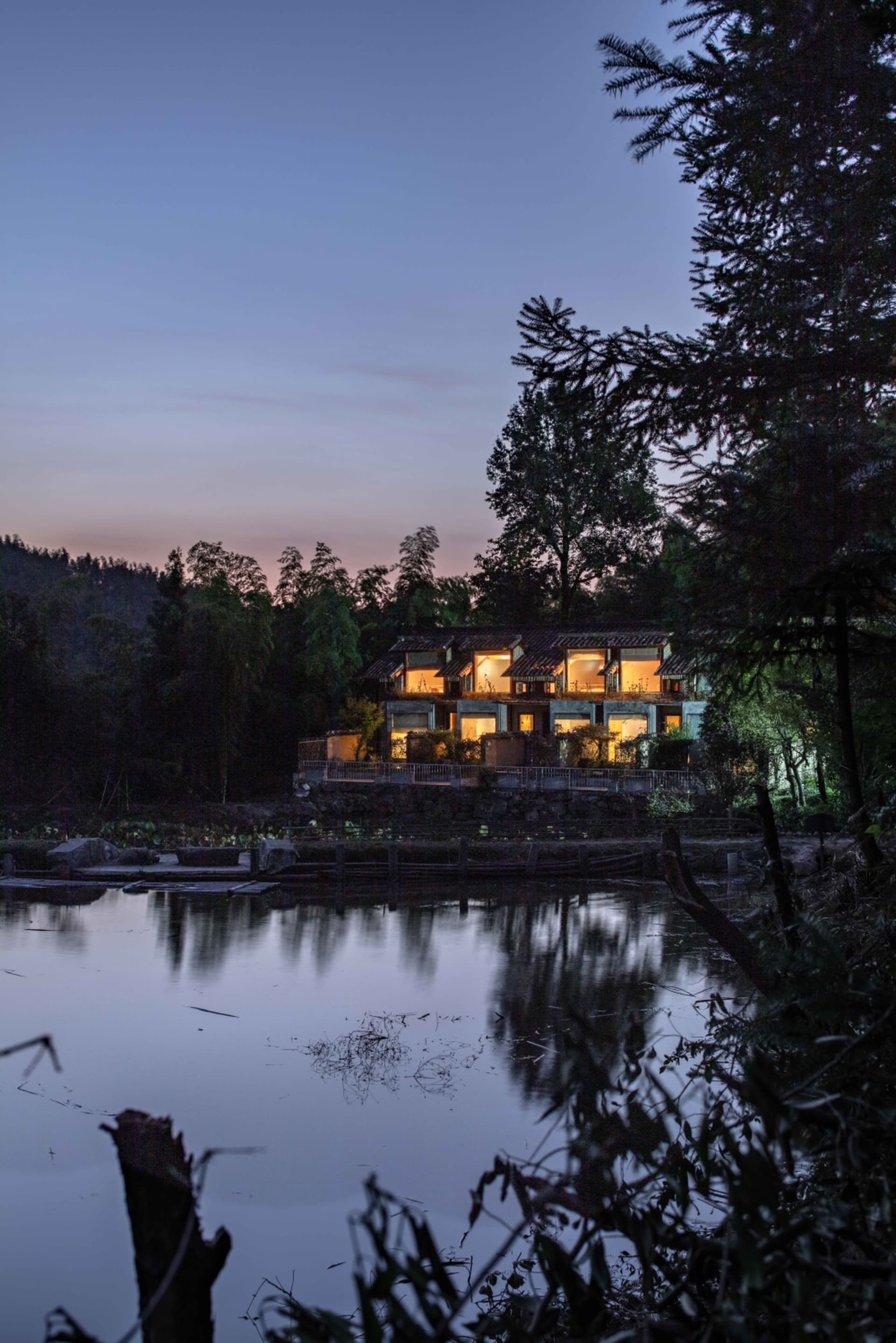 A modern house with concrete exterior and a serene waterfront view.