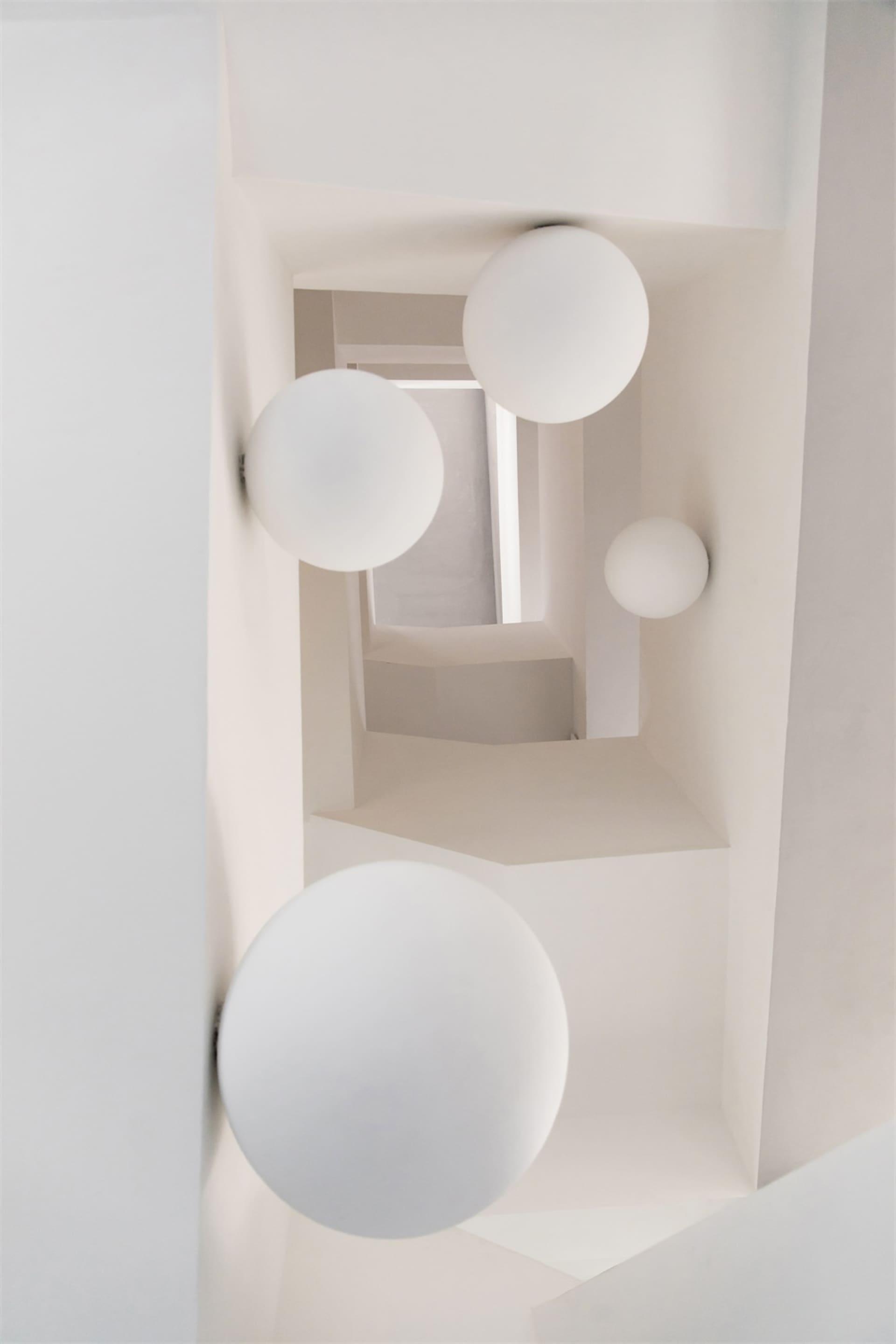 Modern minimalist interior with white walls and spherical light fixtures.