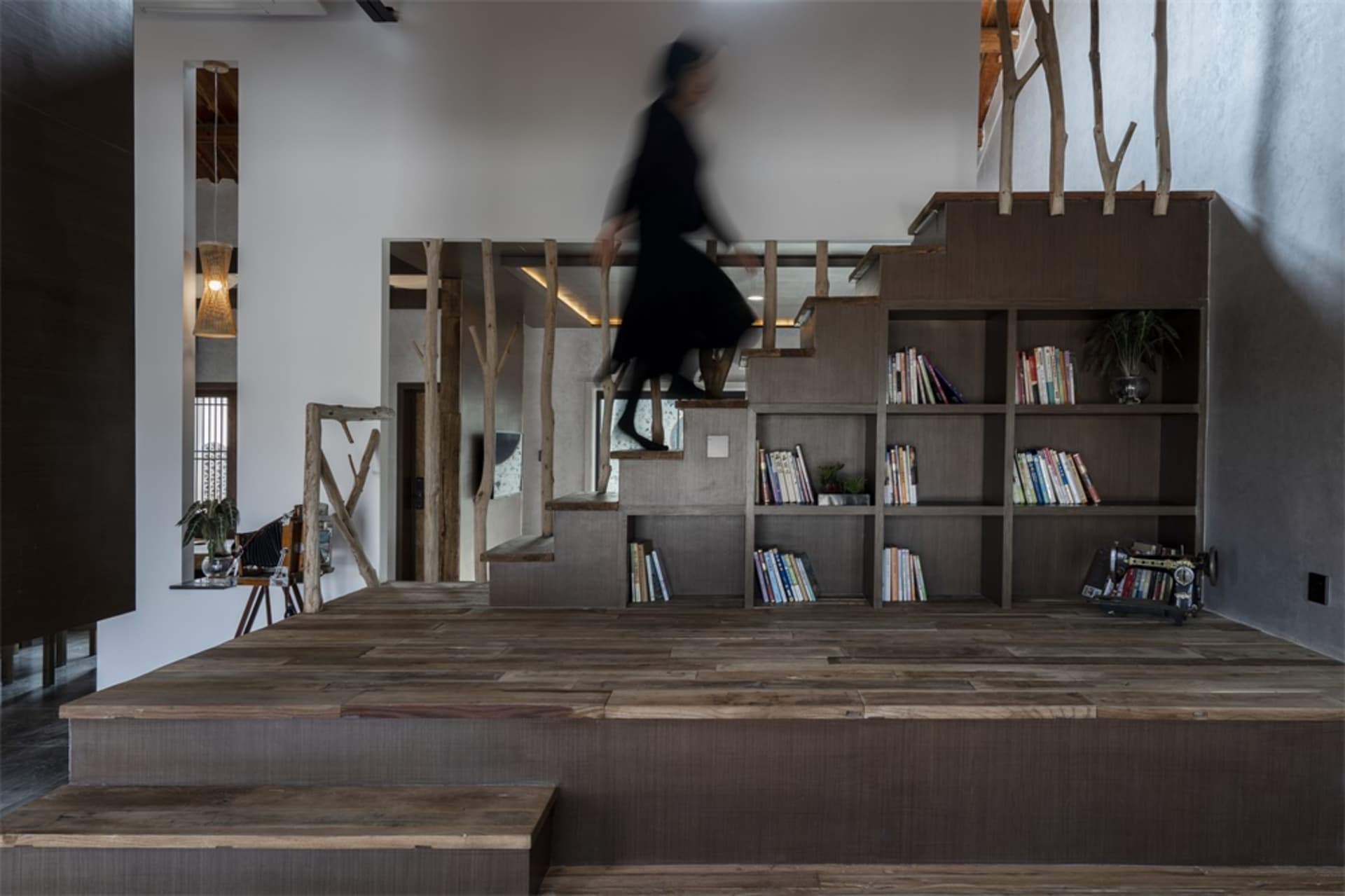 A modern office library with wooden flooring, concrete walls, and metallic shelving units.
