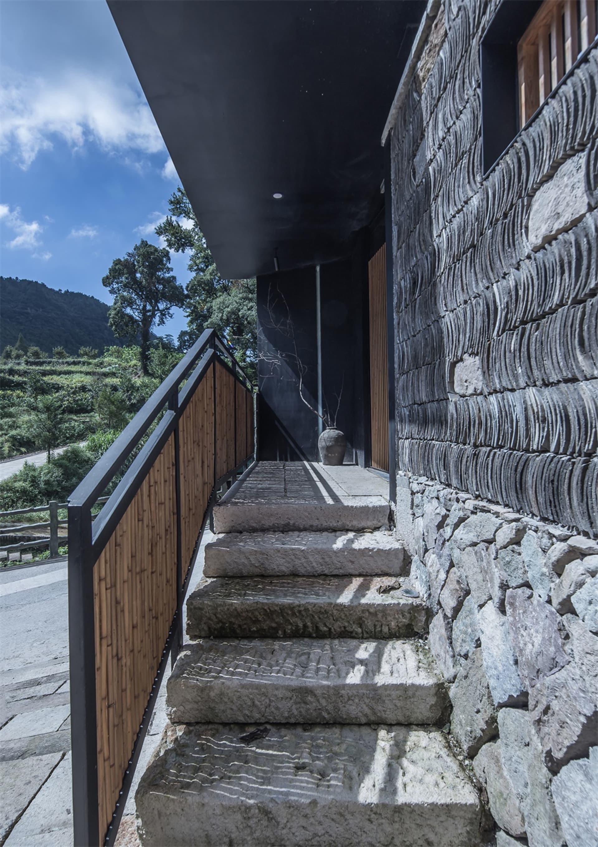 A stone staircase with a wooden railing leading up to a building exterior.