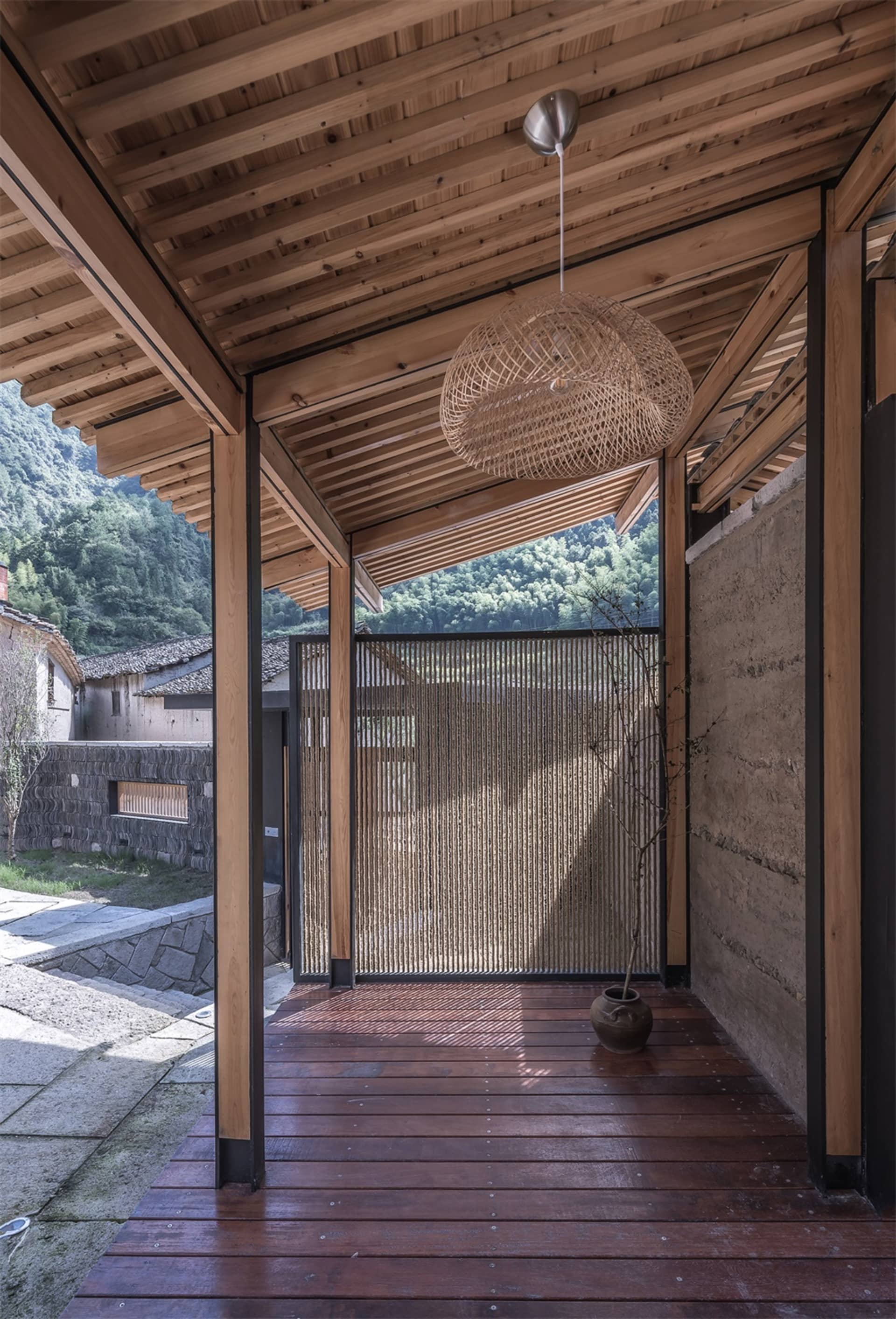 簡約住宅外觀，設有木質門廊與編織燈具。
