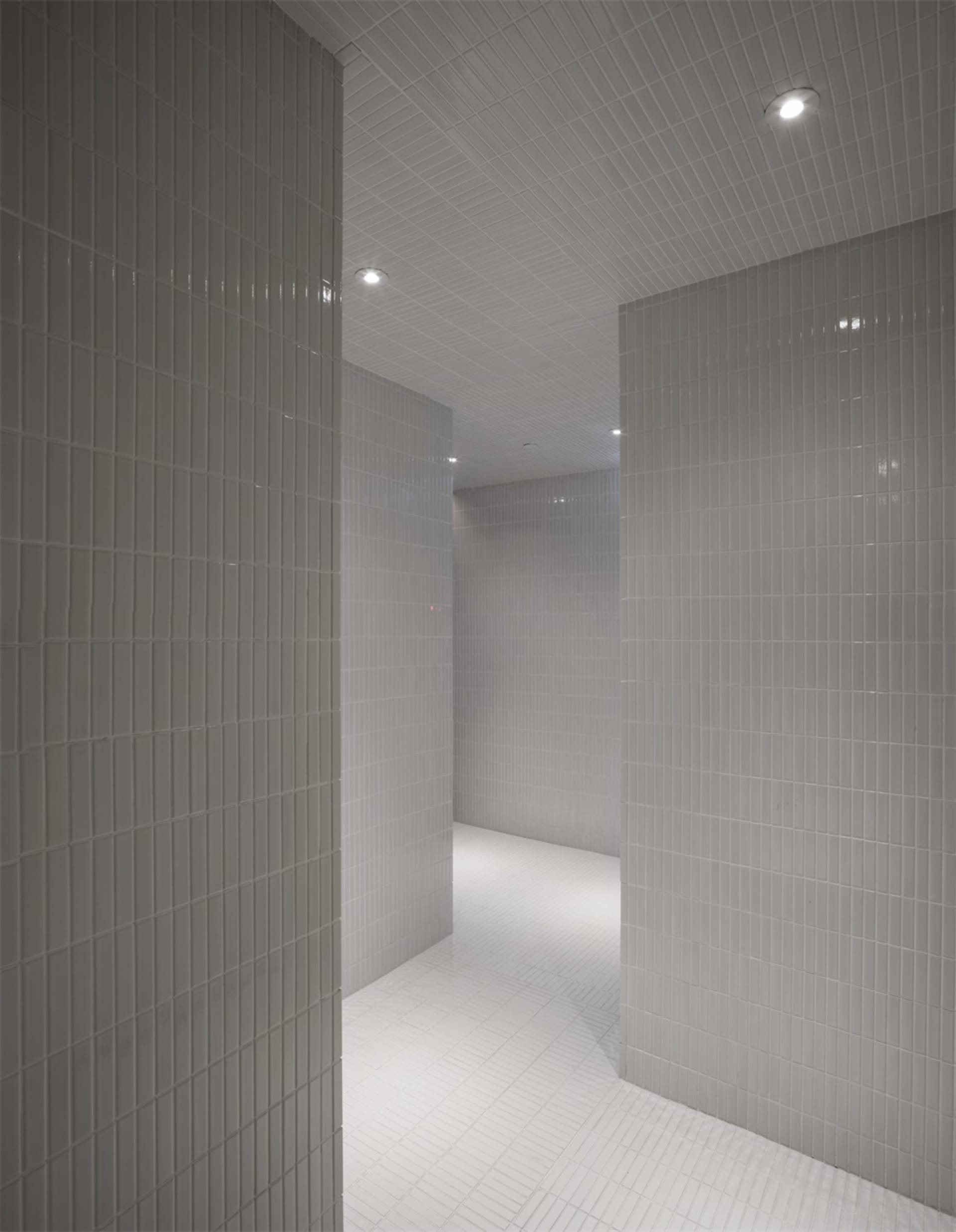 Interior view of a minimalist white tile bathroom with a clean, uncluttered design.
