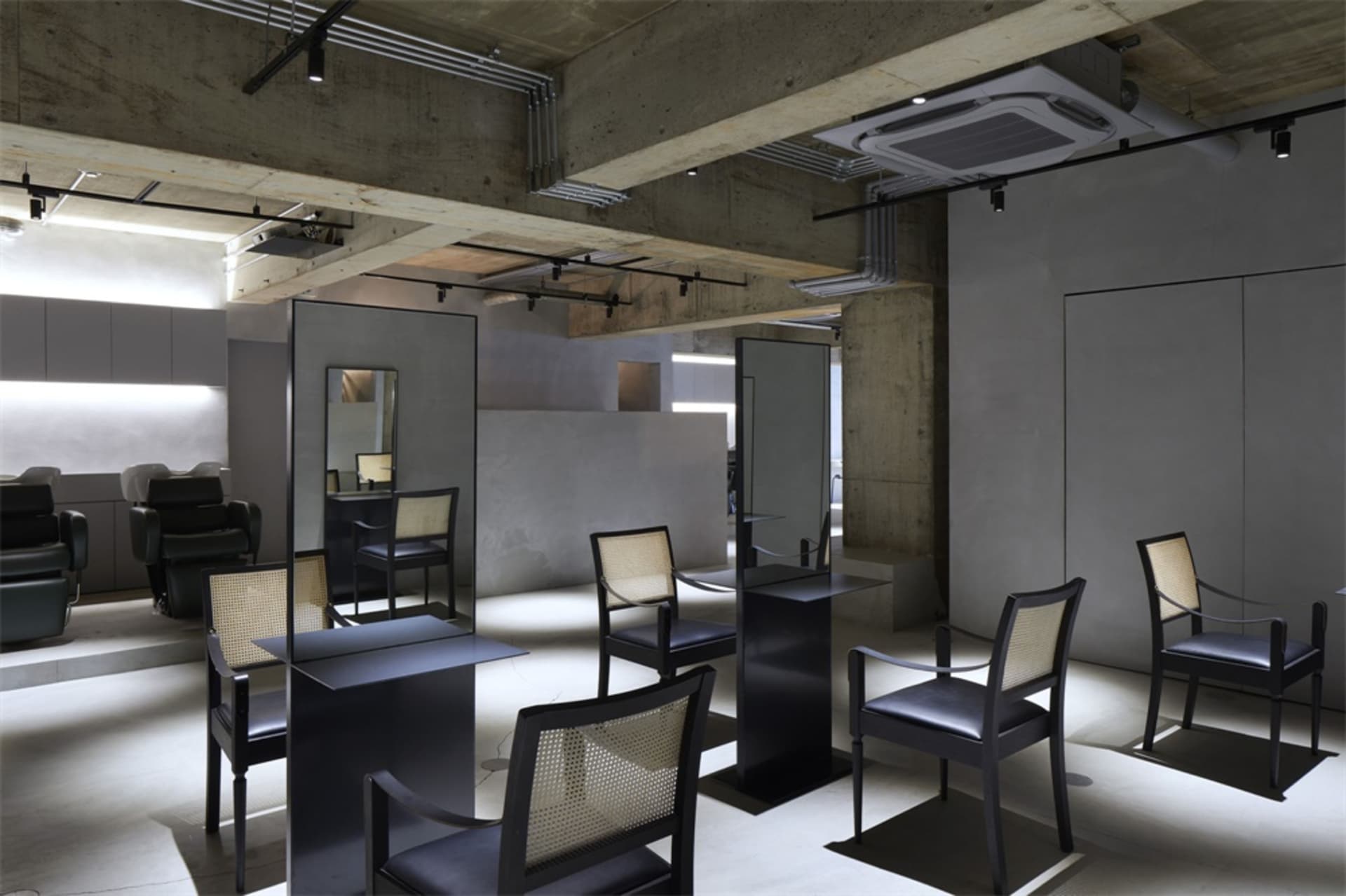 A modern hair salon with concrete walls and steel furniture.