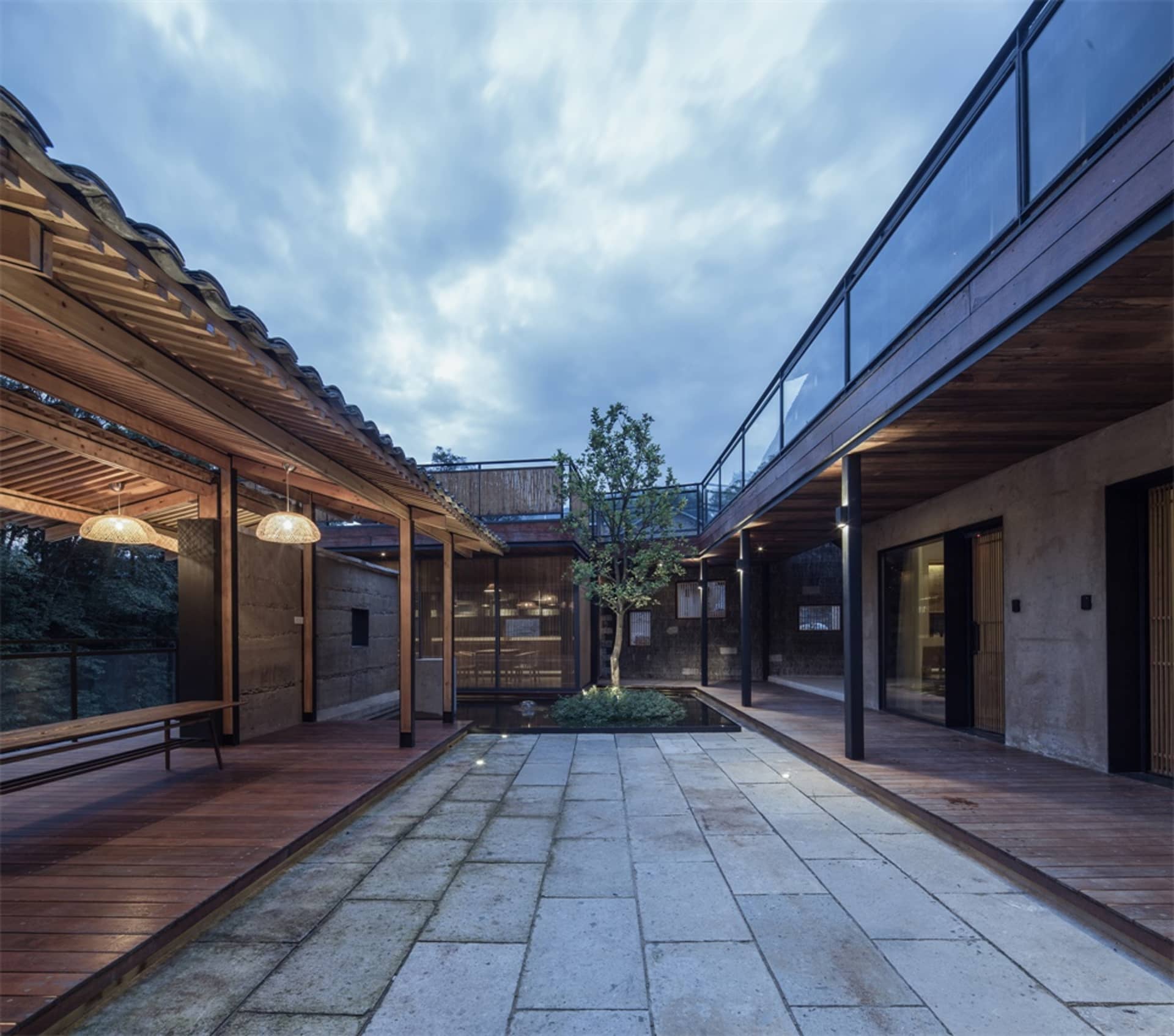 現代工業風住宅室內，採用木質與混凝土材質，並設有中央庭院與樹木。