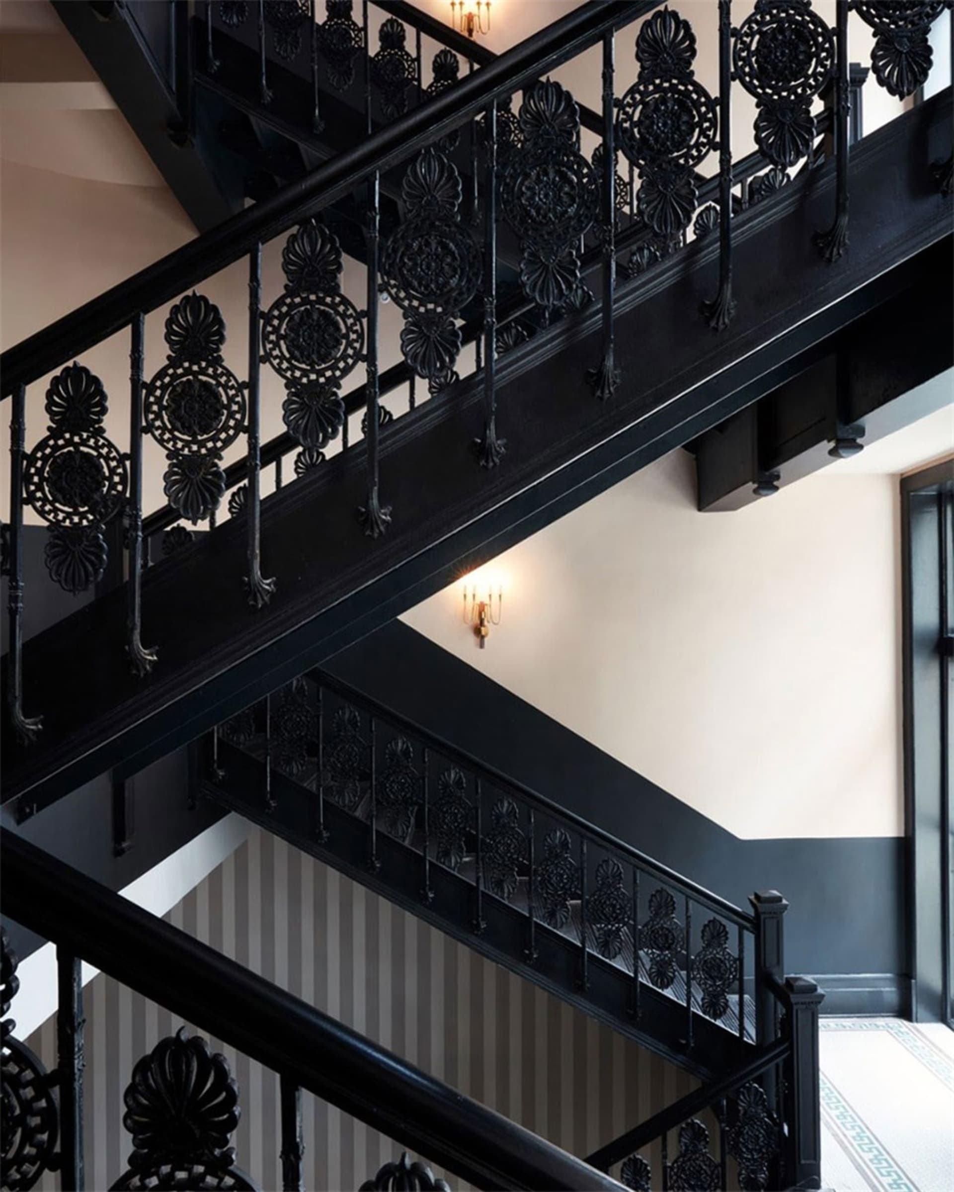 A grand black iron staircase with ornate railings and lighting in an interior setting.