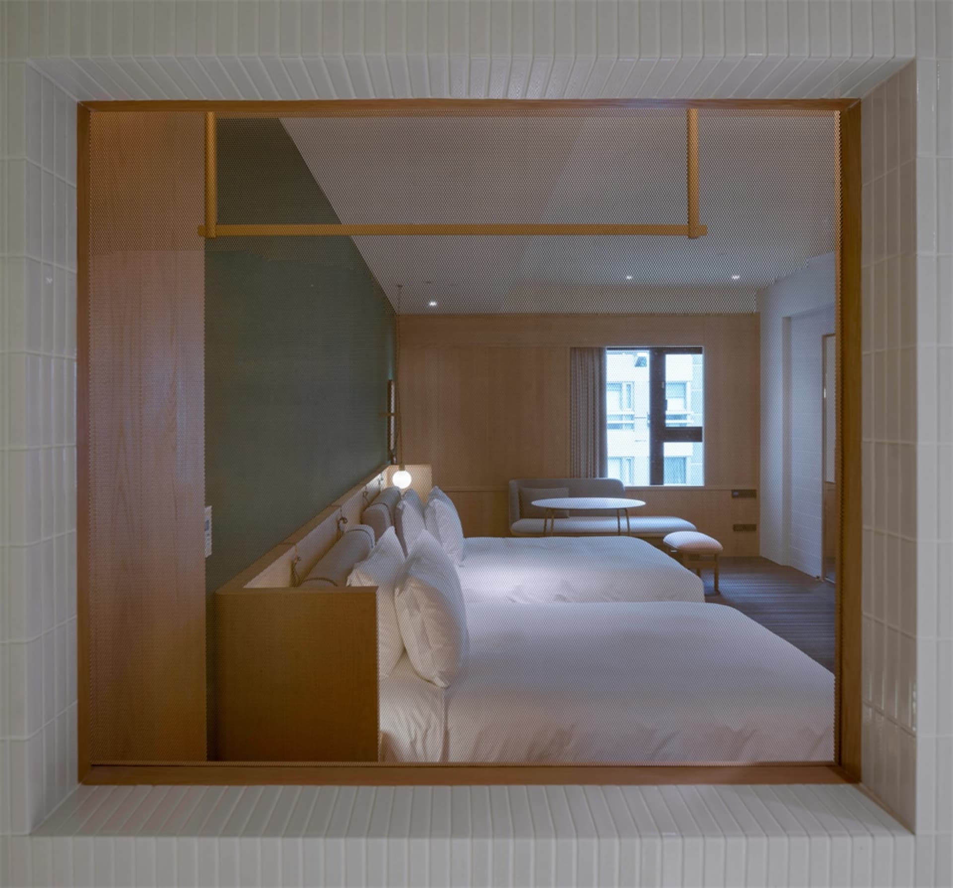Modern minimalist bedroom with white bedding and wooden furniture, featuring a frame and light fixture.