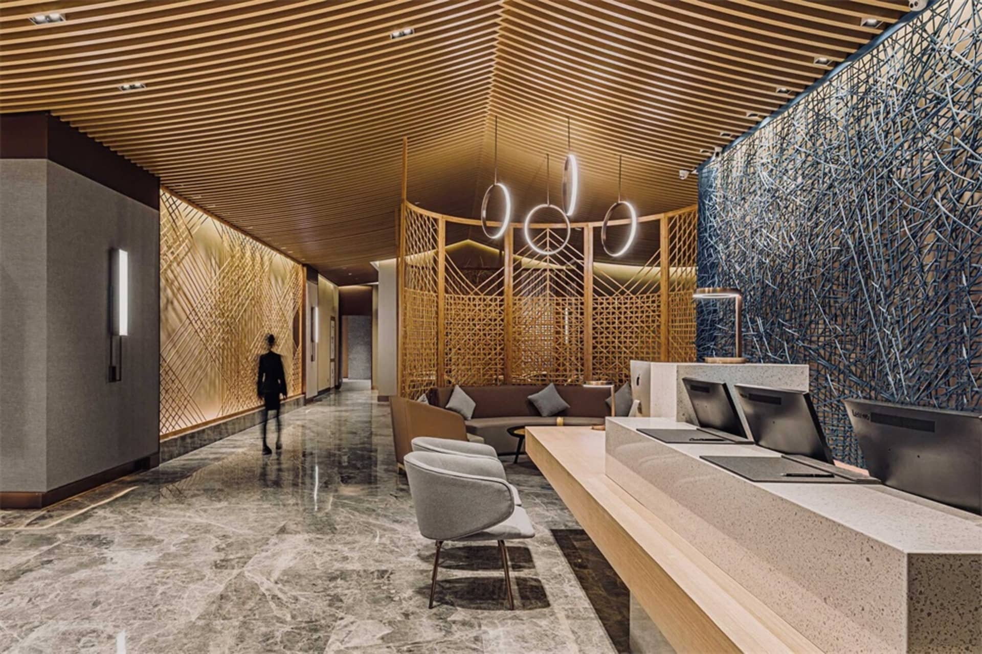Modern hotel reception area featuring wood cladding, marble accents, and cement floors.