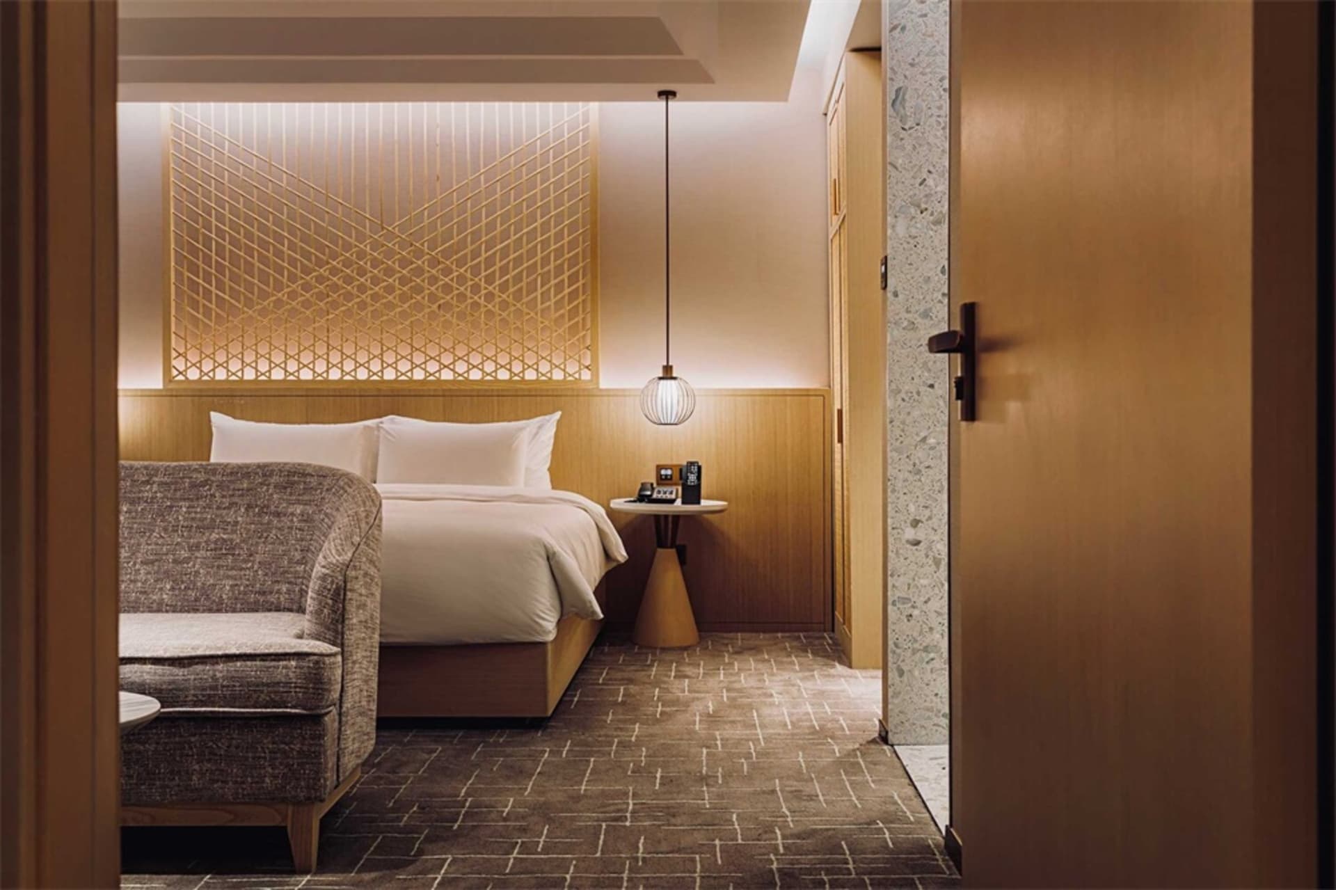 A modern hotel bedroom with a wooden accent wall and a neatly made bed.