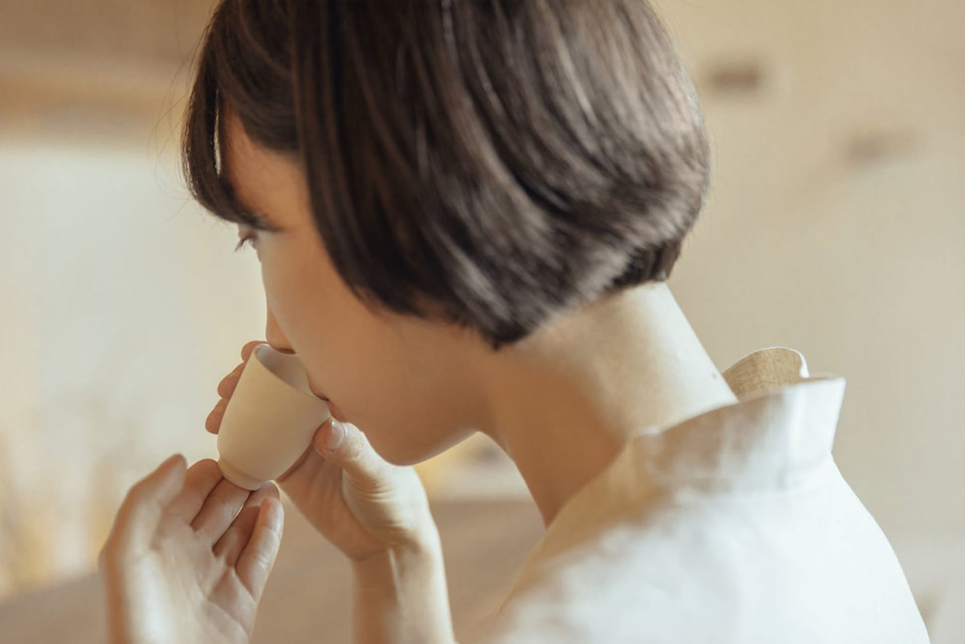 人物正從陶瓷杯中飲用飲料