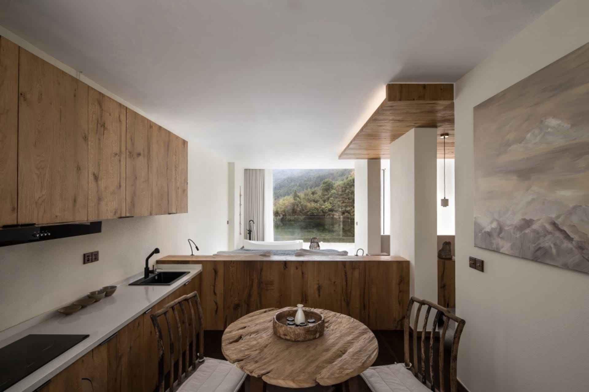 Modern minimalist kitchen with wooden cabinets and table, featuring a view of a serene landscape through a large window.