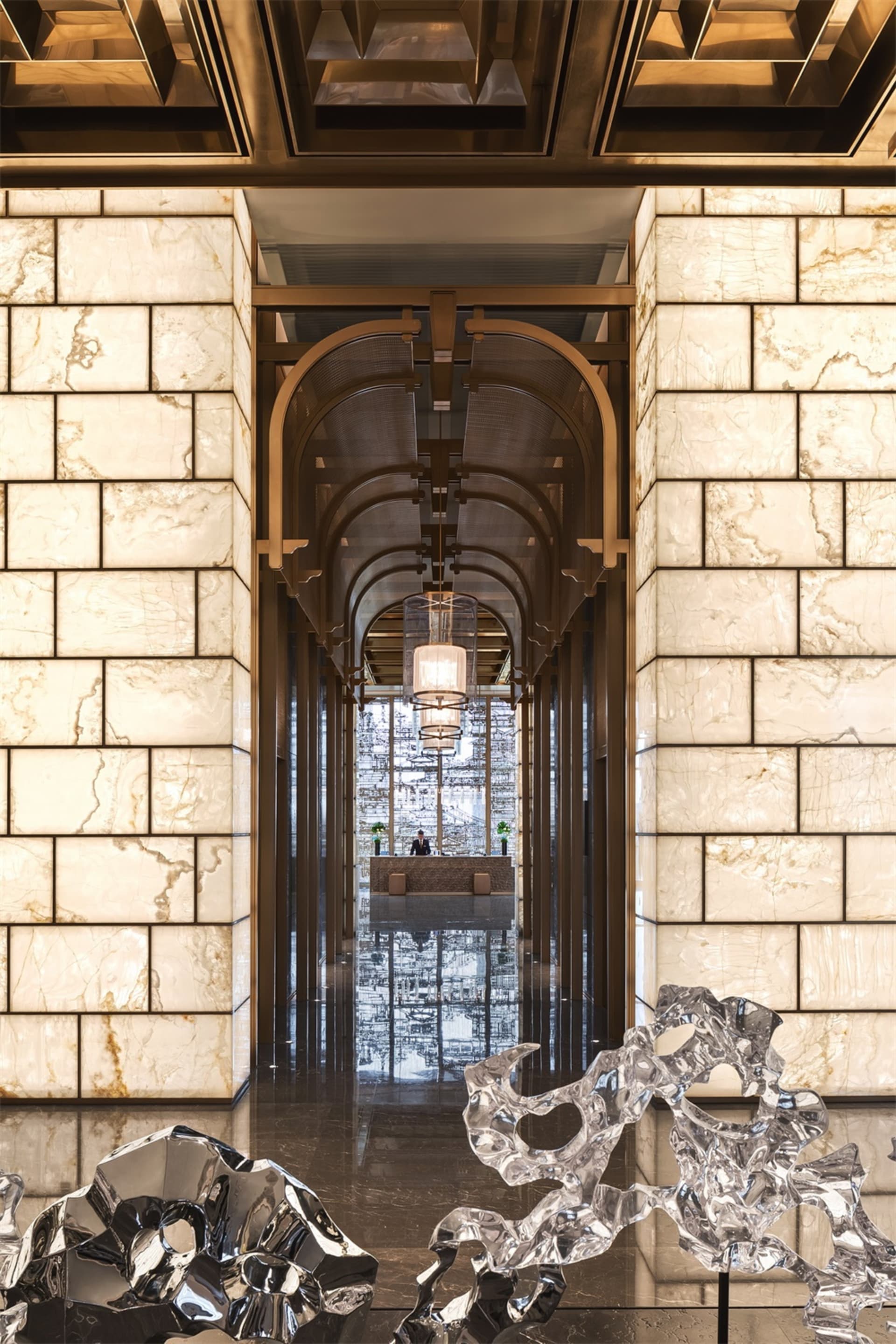 Modern lobby featuring a grand marble entranceway with multiple archways and illuminated hanging lamps.