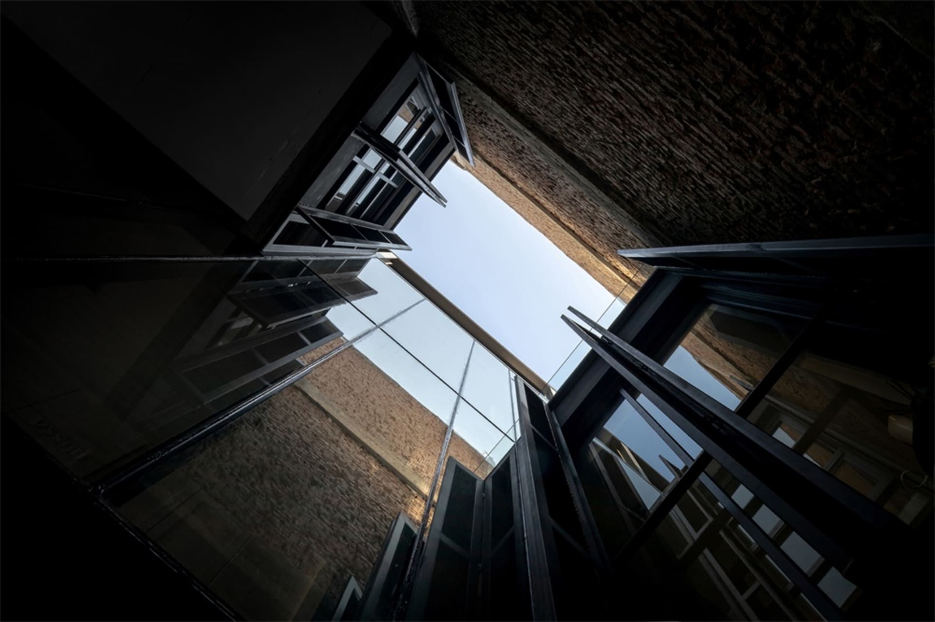Steel-glass-brick building inner space looking up towards the sky.