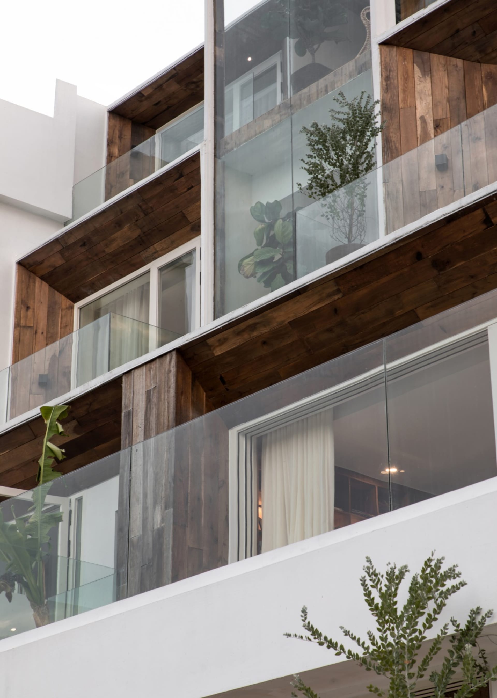 A modern house with glass windows, wooden balconies, and concrete columns.