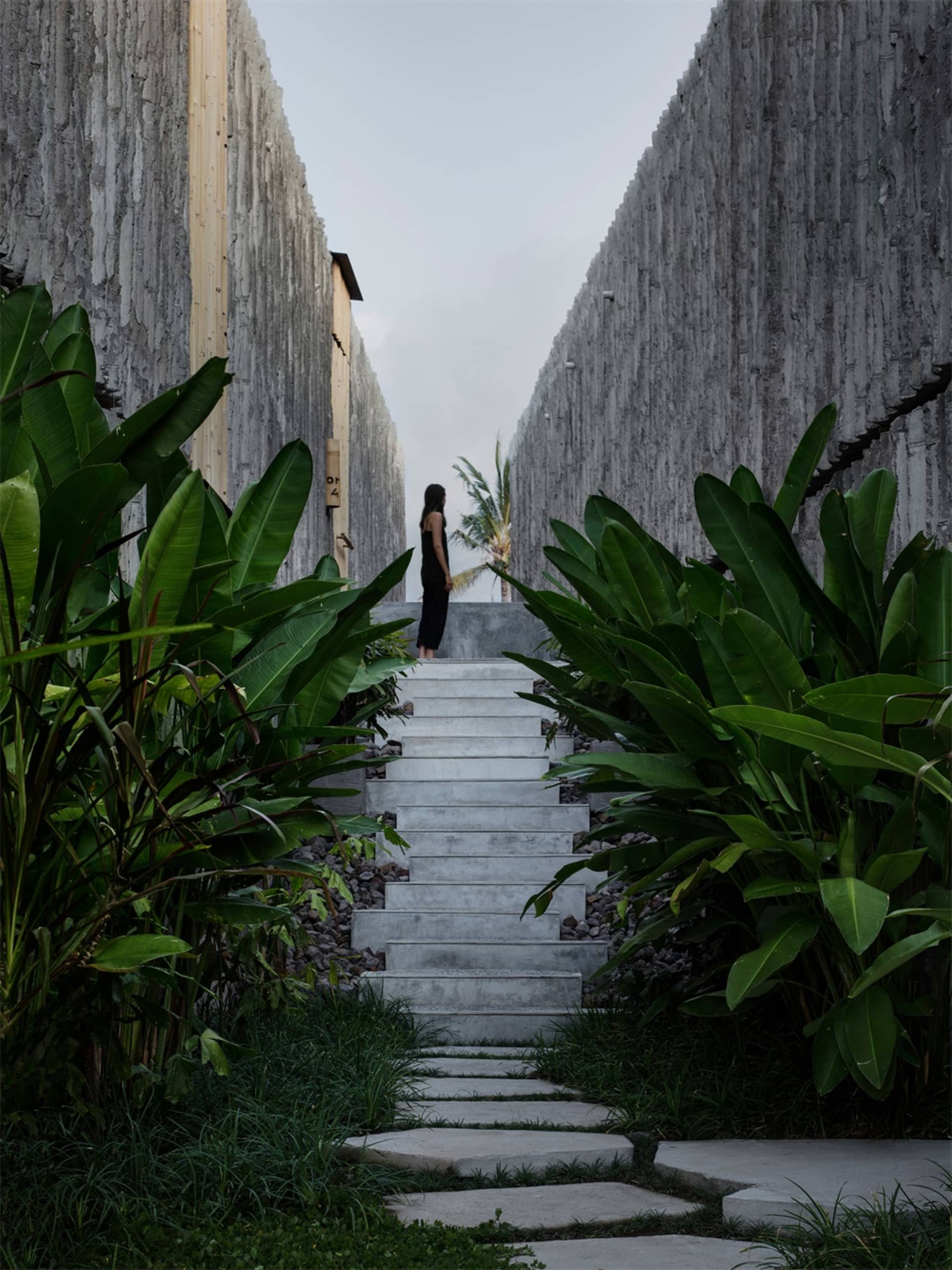 A minimalist landscape featuring a concrete pathway bordered by lush greenery.