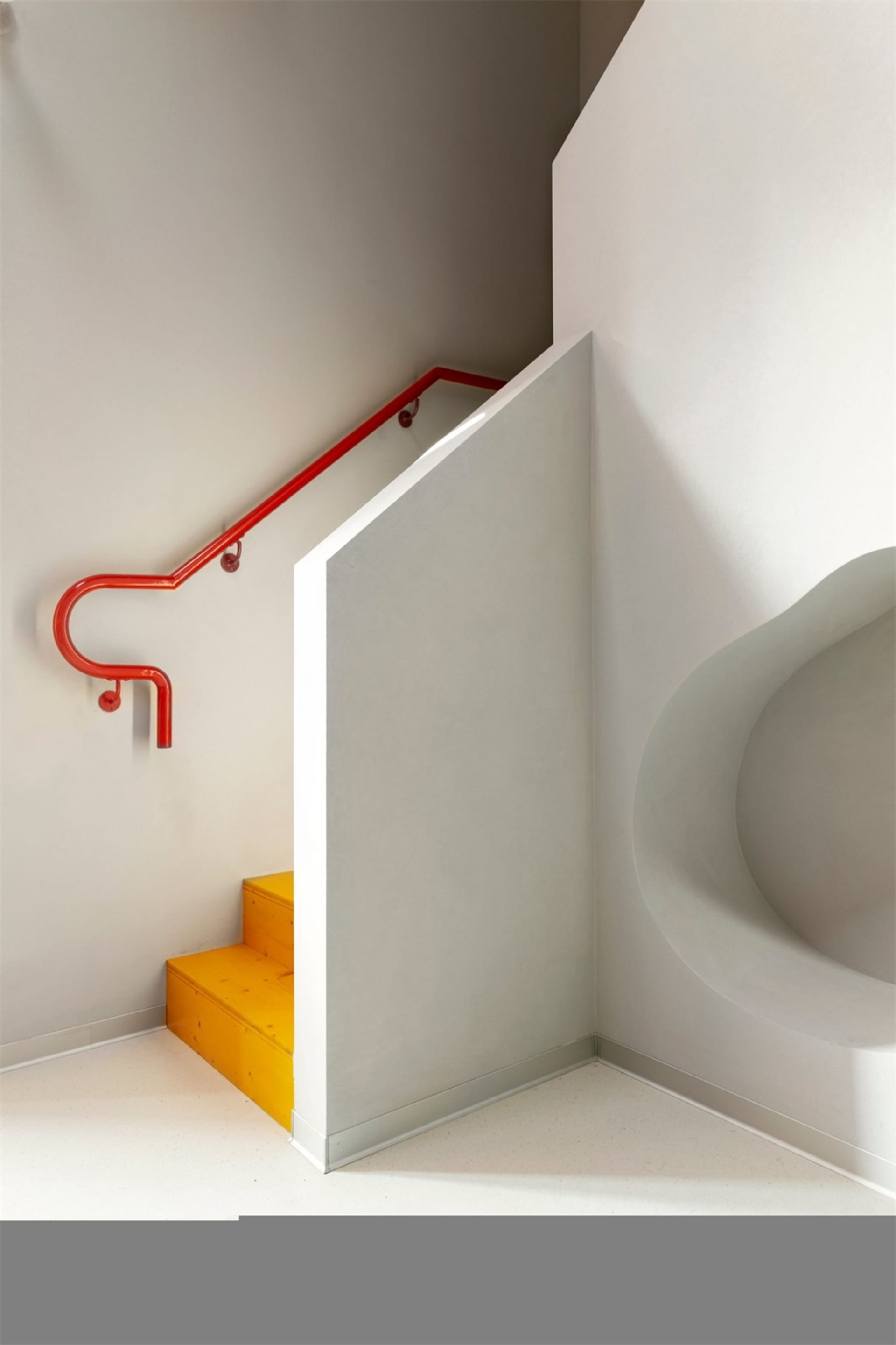 A metallic red staircase with a curved red handrail.