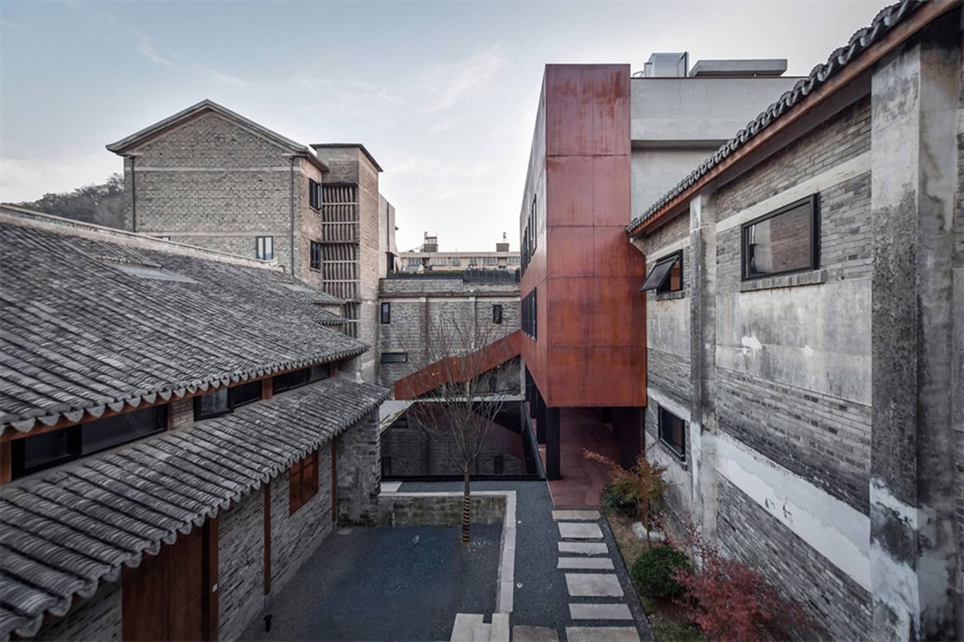 A modern residential pavilion with brick and concrete walls, featuring a courtyard and pathway.