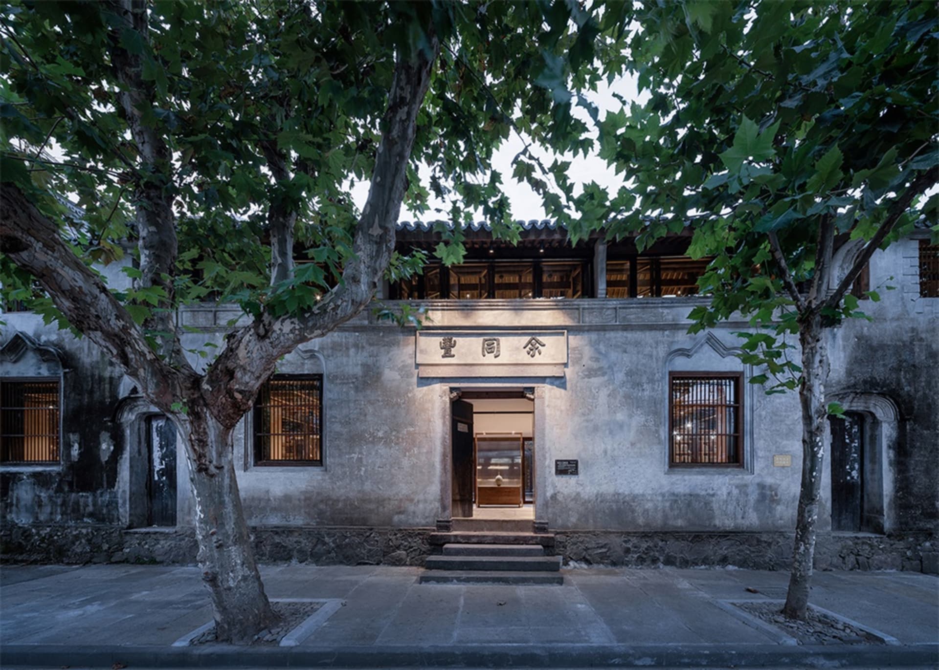 Traditional building with weathered stone facade and large windows.