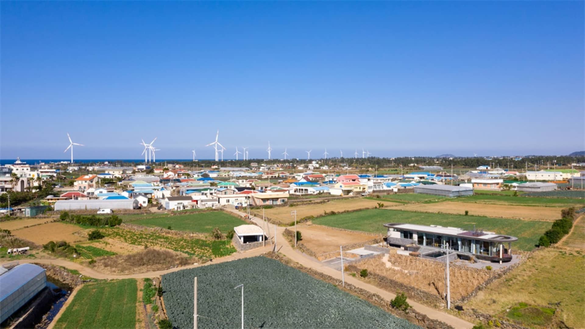 An aerial view of a small town with wind turbines in the background, representing sustainable energy development.