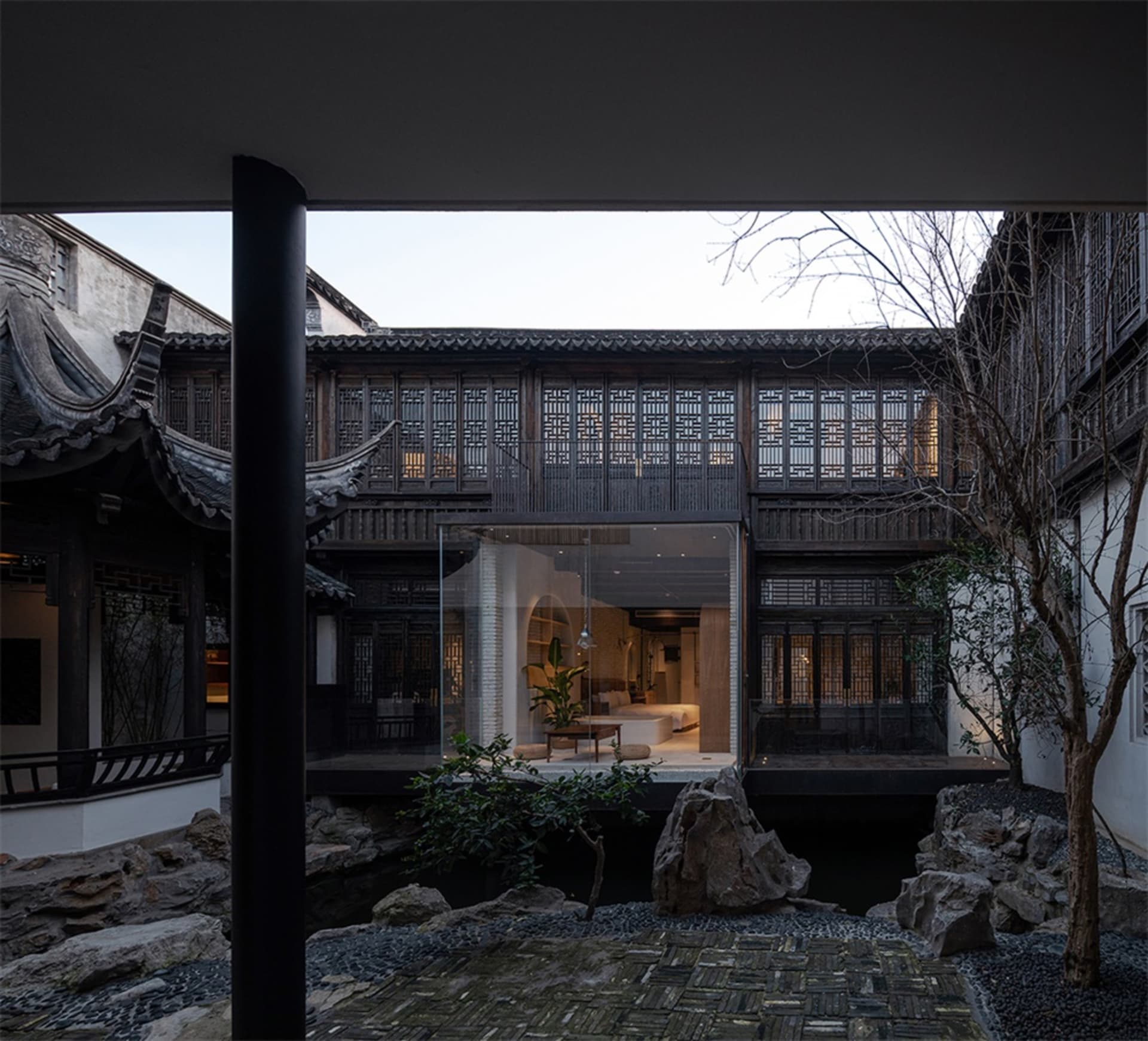 A traditional Chinese garden with wooden beams, glass seating, and stone path.